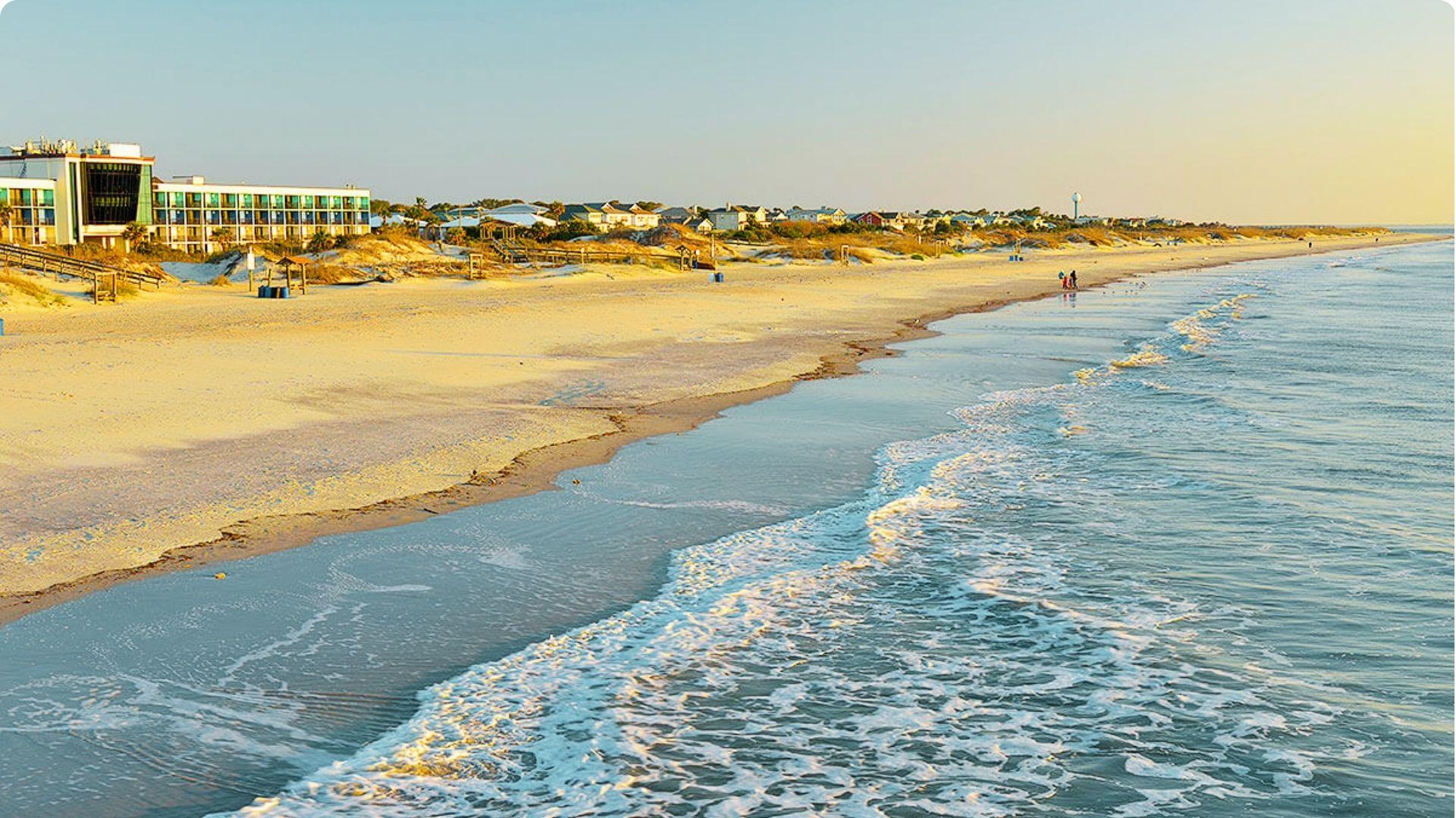 Peaceful shoreline at Tybee Island Beach with gentle waves, sandy dunes, and beachfront accommodations.