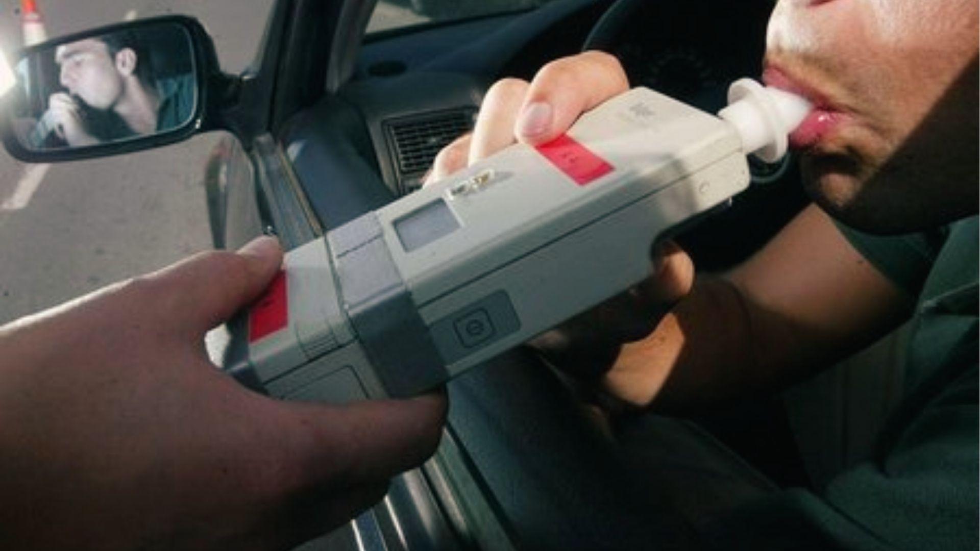 Driver blowing into breathalyzer in car, a test used to enforce Georgia's 0.08 BAC alcohol limit.