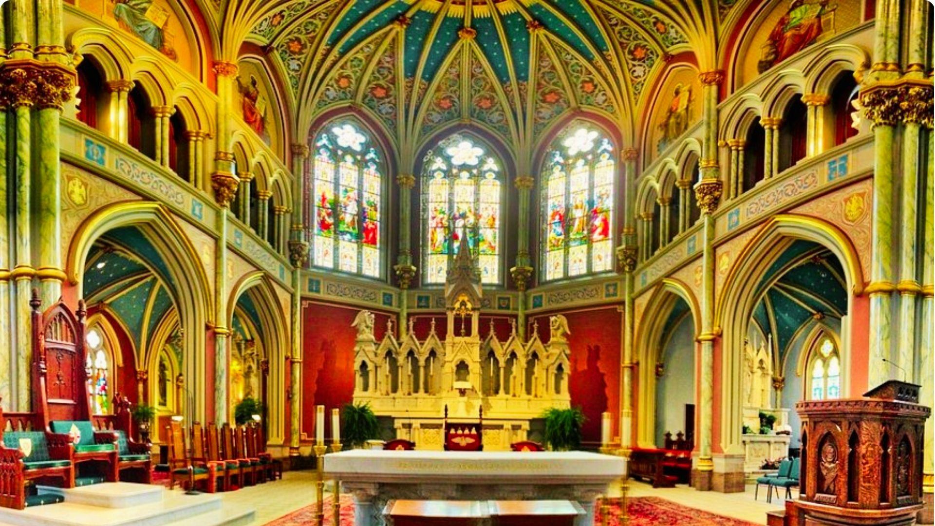 Ornate cathedral interior in Savannah featuring stained glass windows, Gothic arches, and a grand altar.
