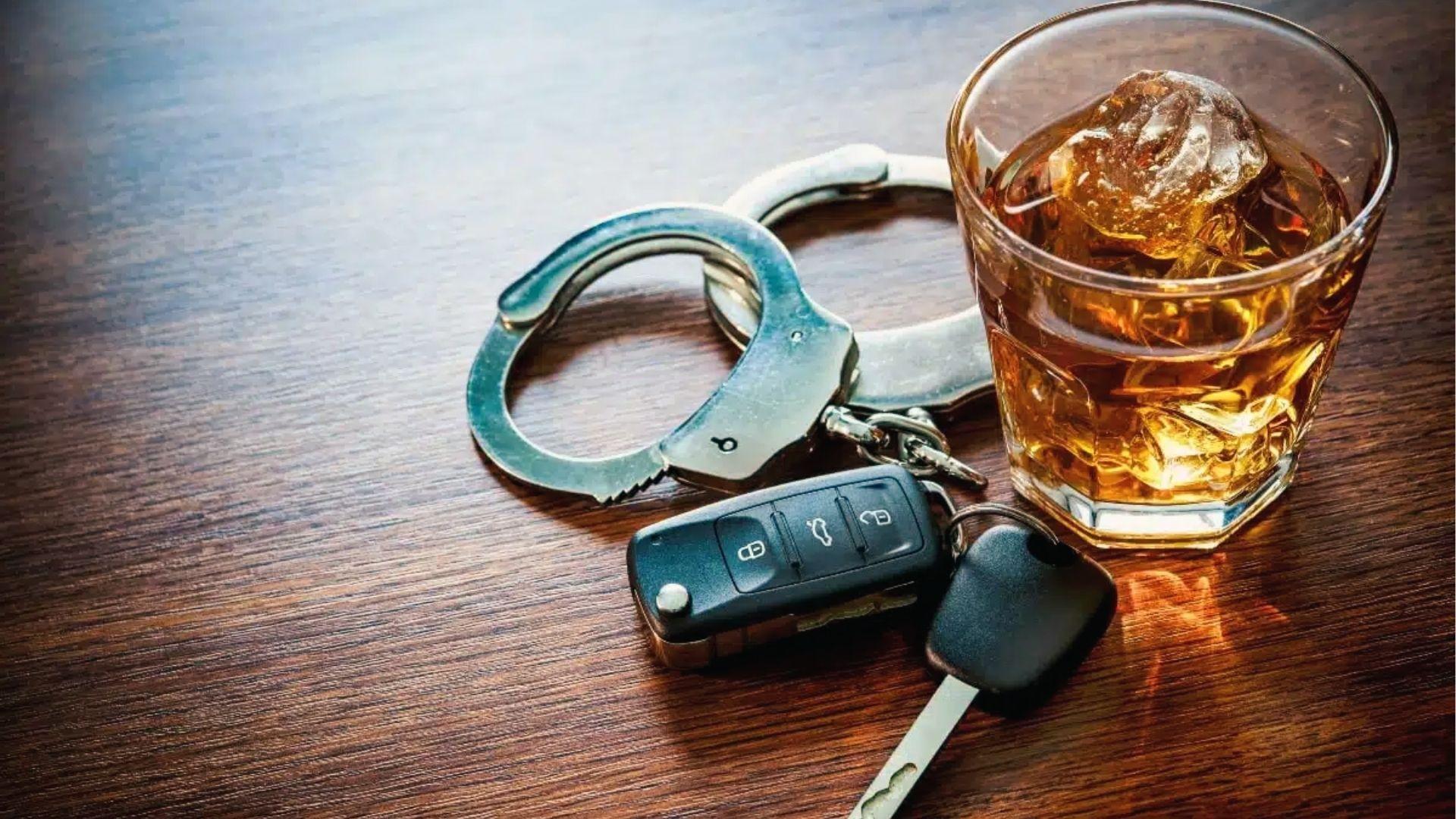 Whiskey with ice, handcuffs, and keys on table, illustrating arrest risk above Georgia's 0.08 BAC.