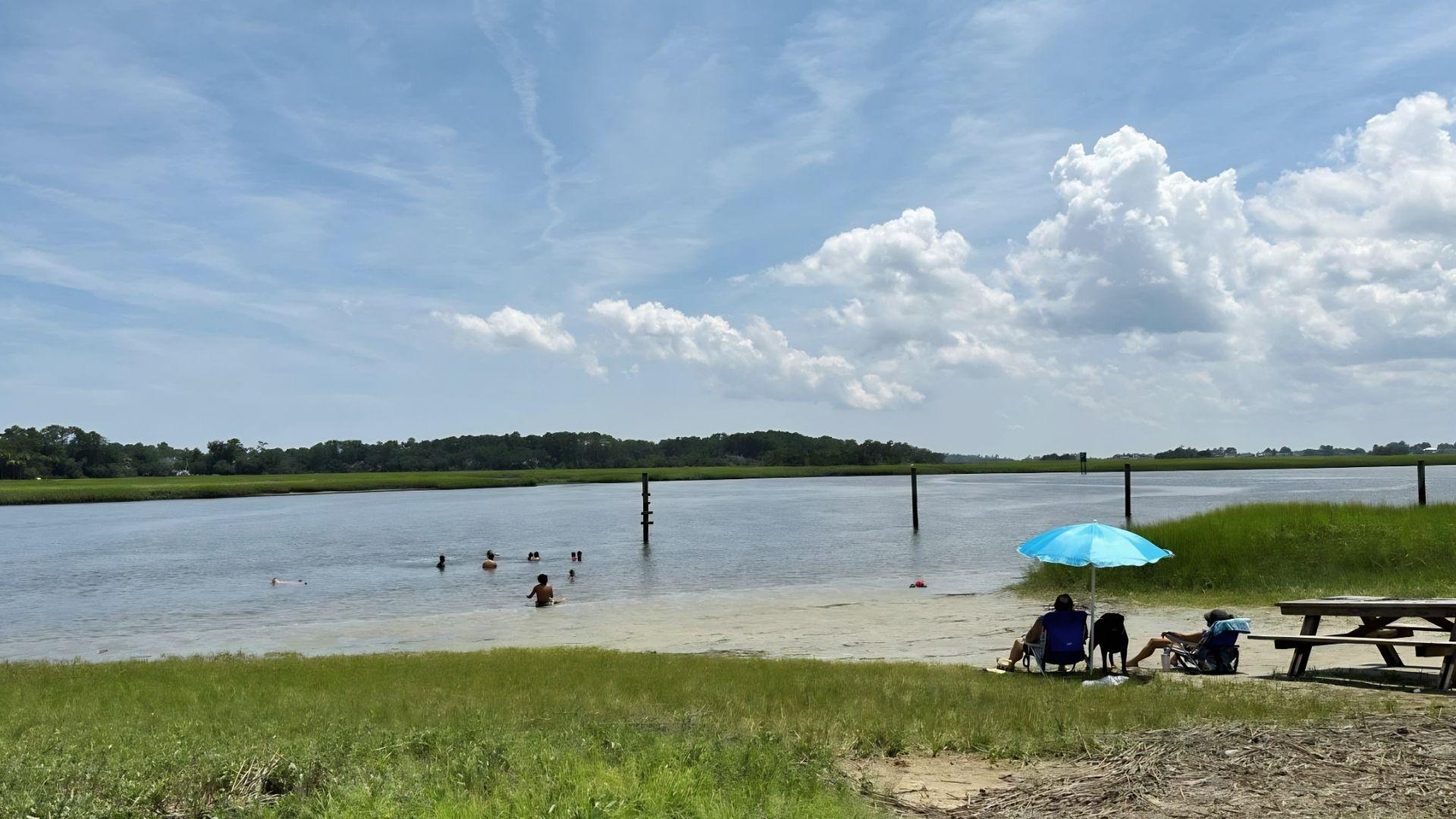 Travelers swimming and relaxing under umbrella at Butterbean Beach Savannah