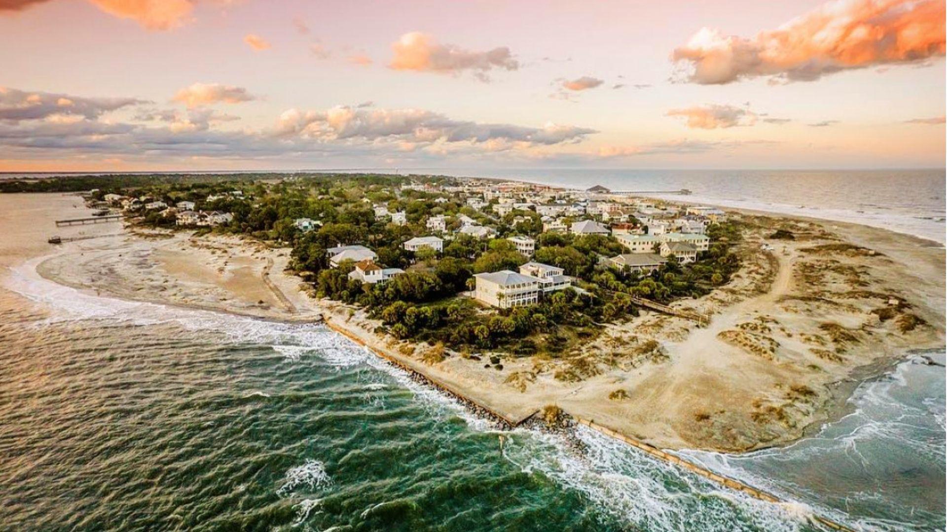 Aerial sunset view of the southern tip of Tybee Island, showing residential homes nestled among trees surrounded by ocean waters.