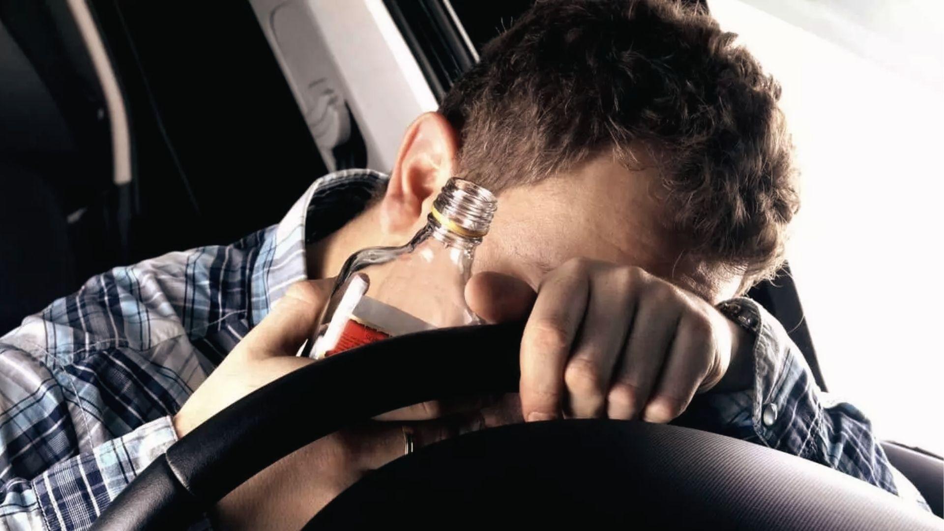 Man slumped over steering wheel with bottle, showing drunk driving risk above Georgia's 0.08 BAC limit.
