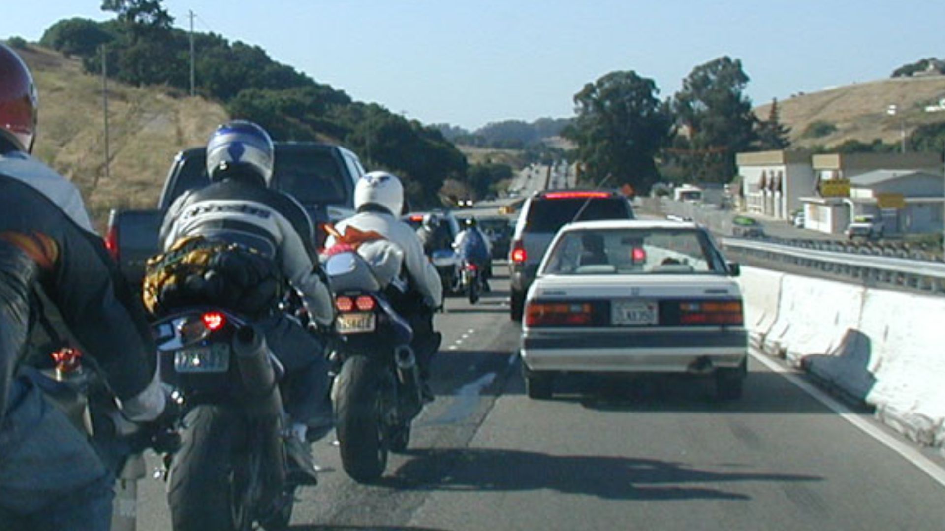 Motorcycle traveling between two lanes of slow-moving traffic to demonstrate lane splitting.