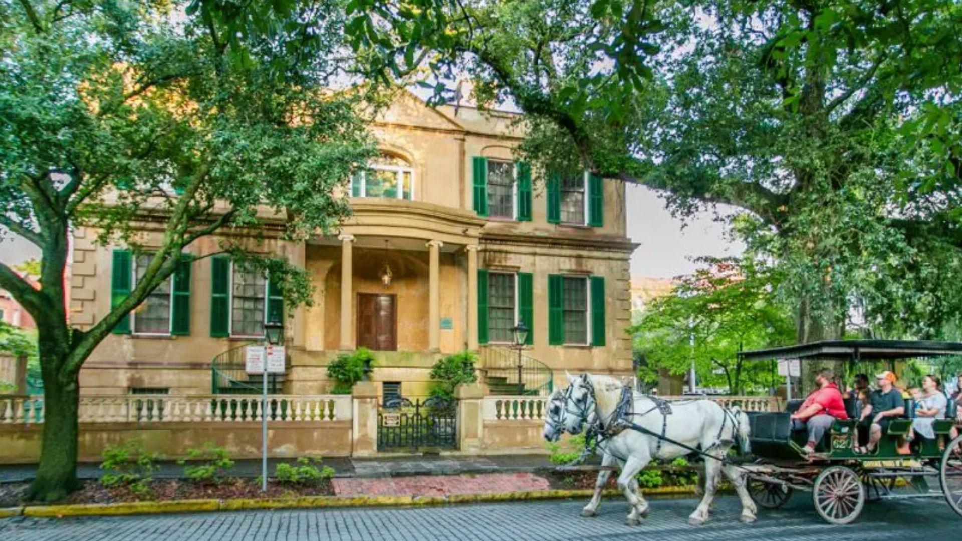 Horse-drawn carriage passing historic Owens-Thomas House in downtown Savannah before traveling to Jekyll Island