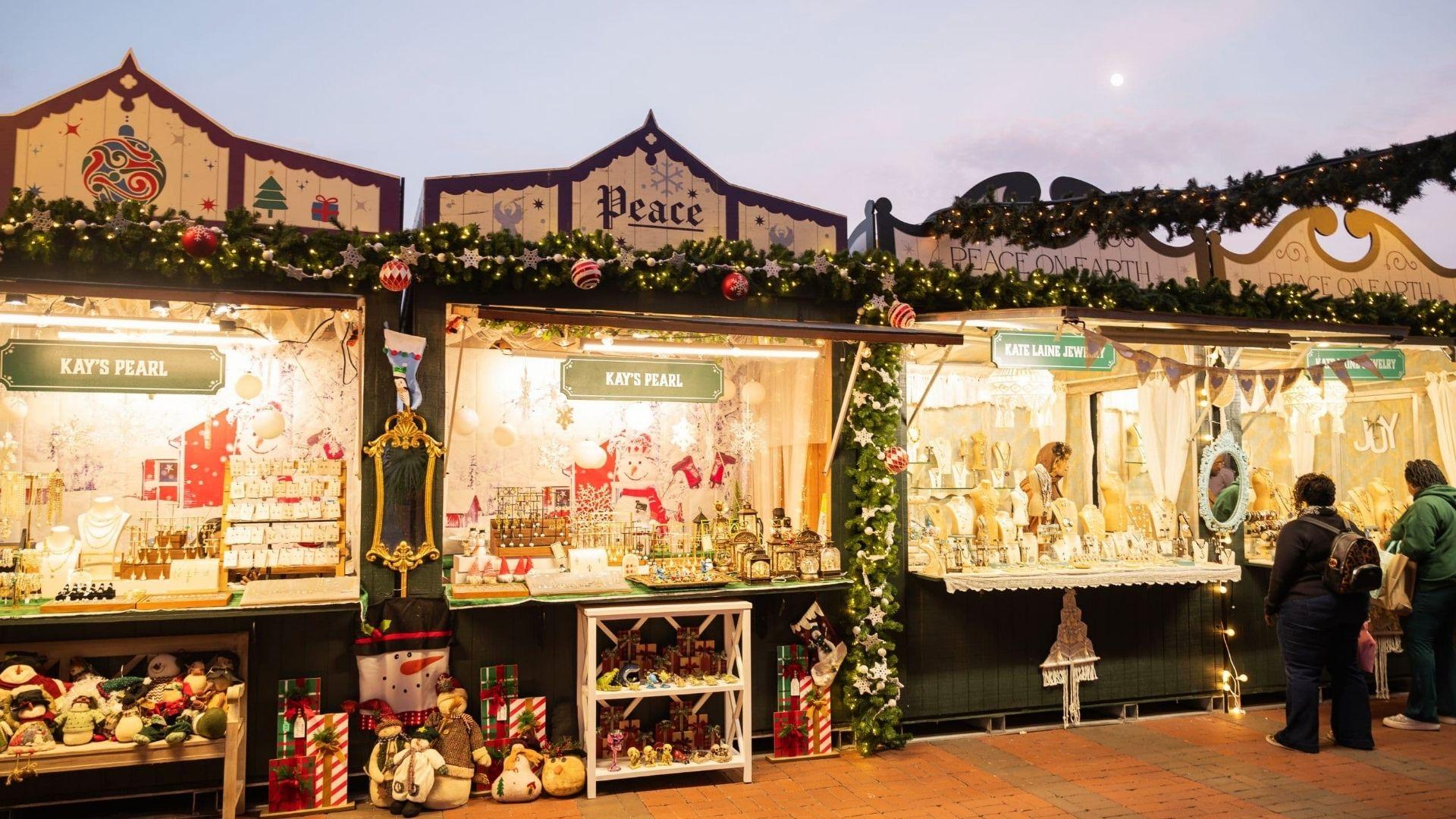 Christmas market stalls in Savannah decorated with lights, garlands, and ornaments selling jewelry and gifts at twilight