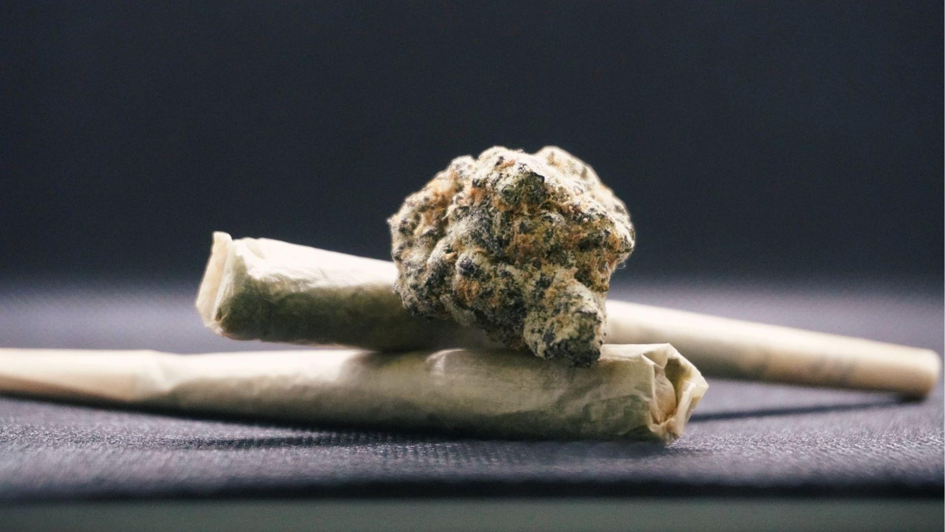 Close-up of rolled joints with cannabis bud on dark surface showing synthetic marijuana use in Georgia.