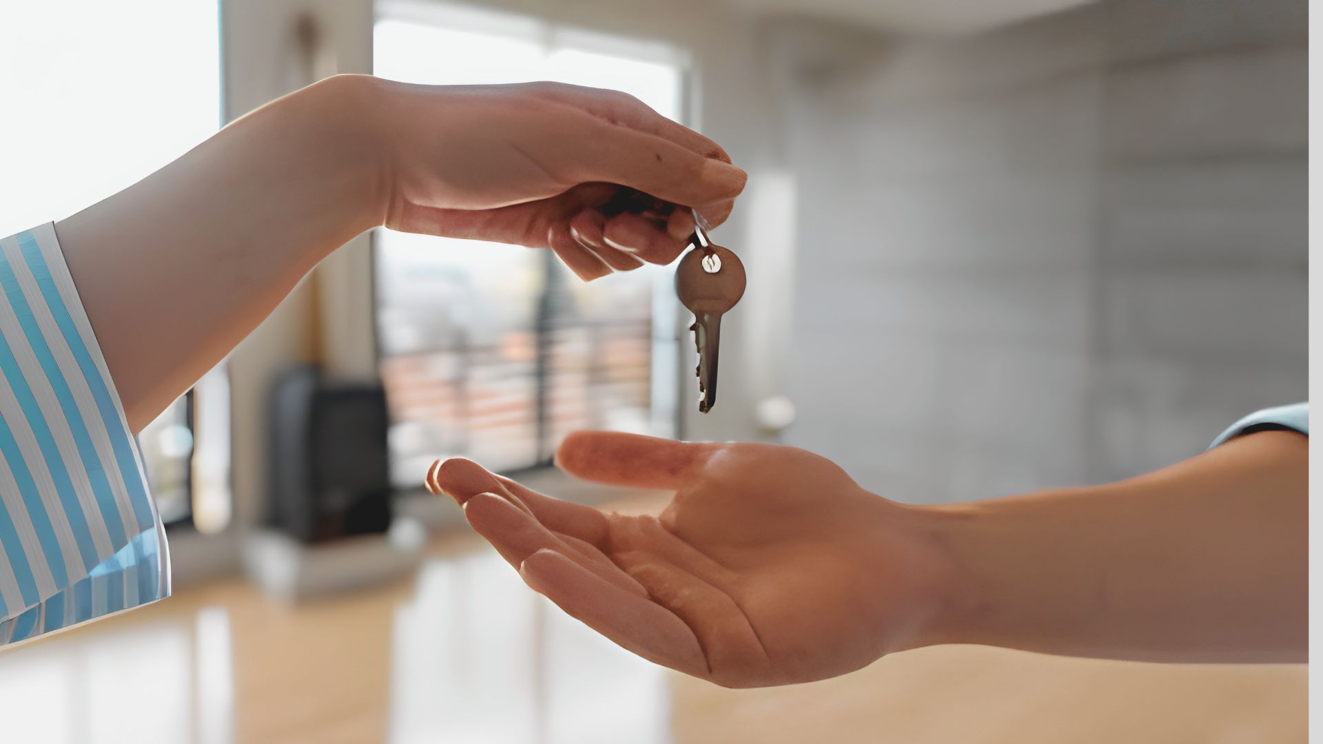 A hand holds out a key with a round tag above another open hand.