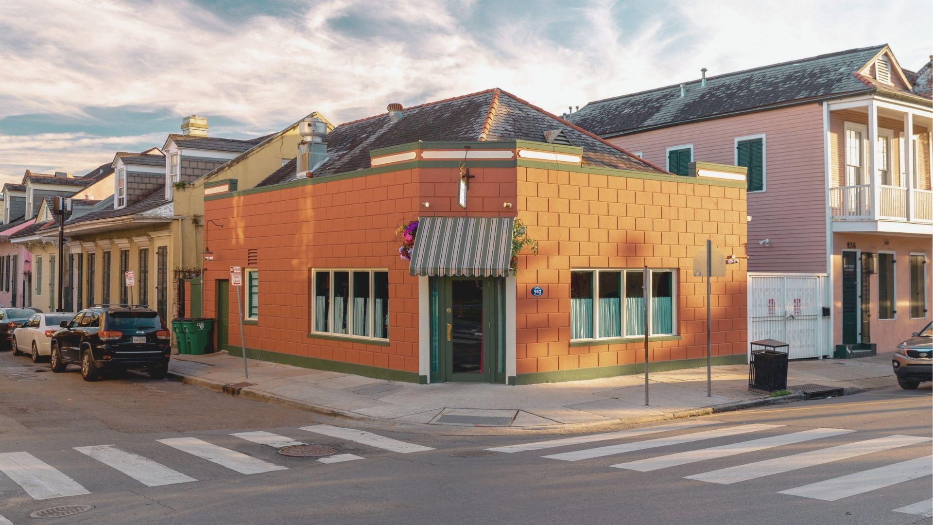 Terracotta corner building with striped awning and French Quarter architecture at golden hour.