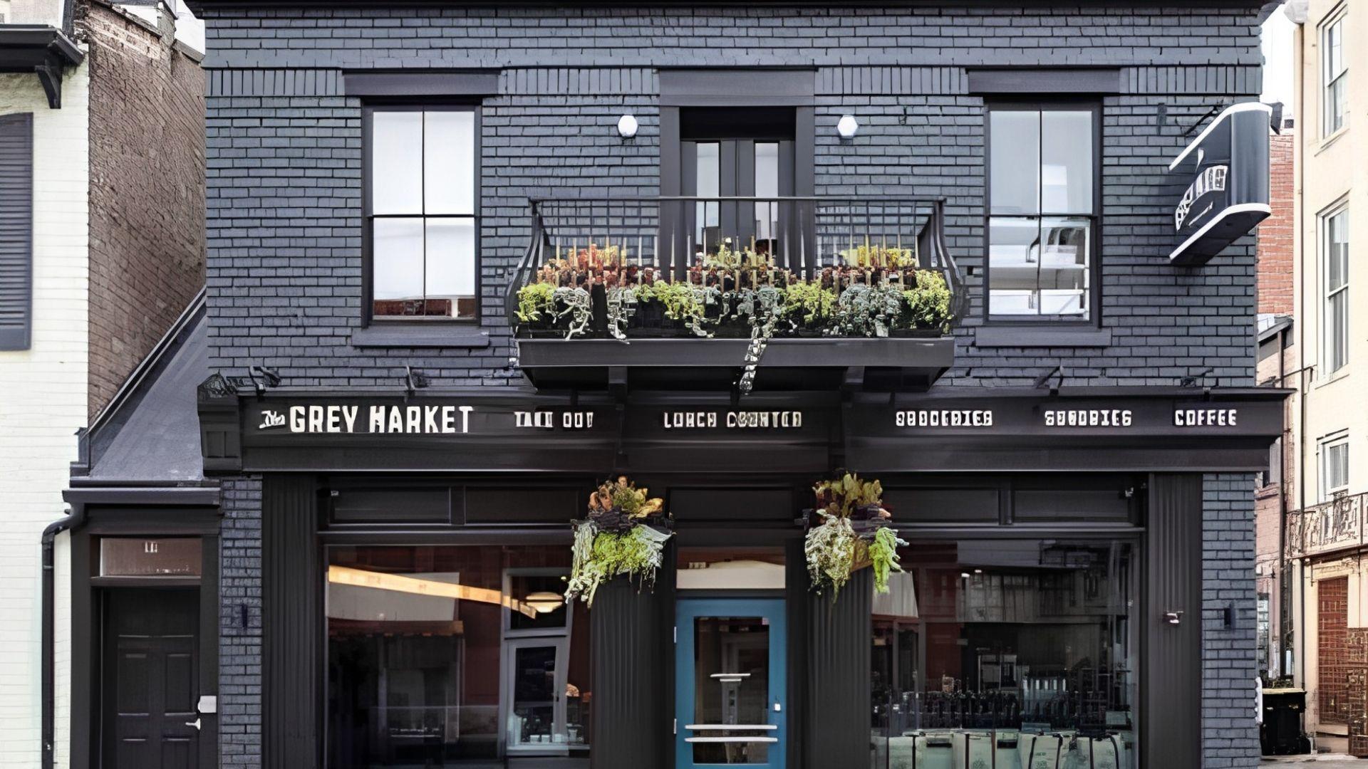 Dark grey brick exterior with black panels and a lined strip of Grey Market written on it.