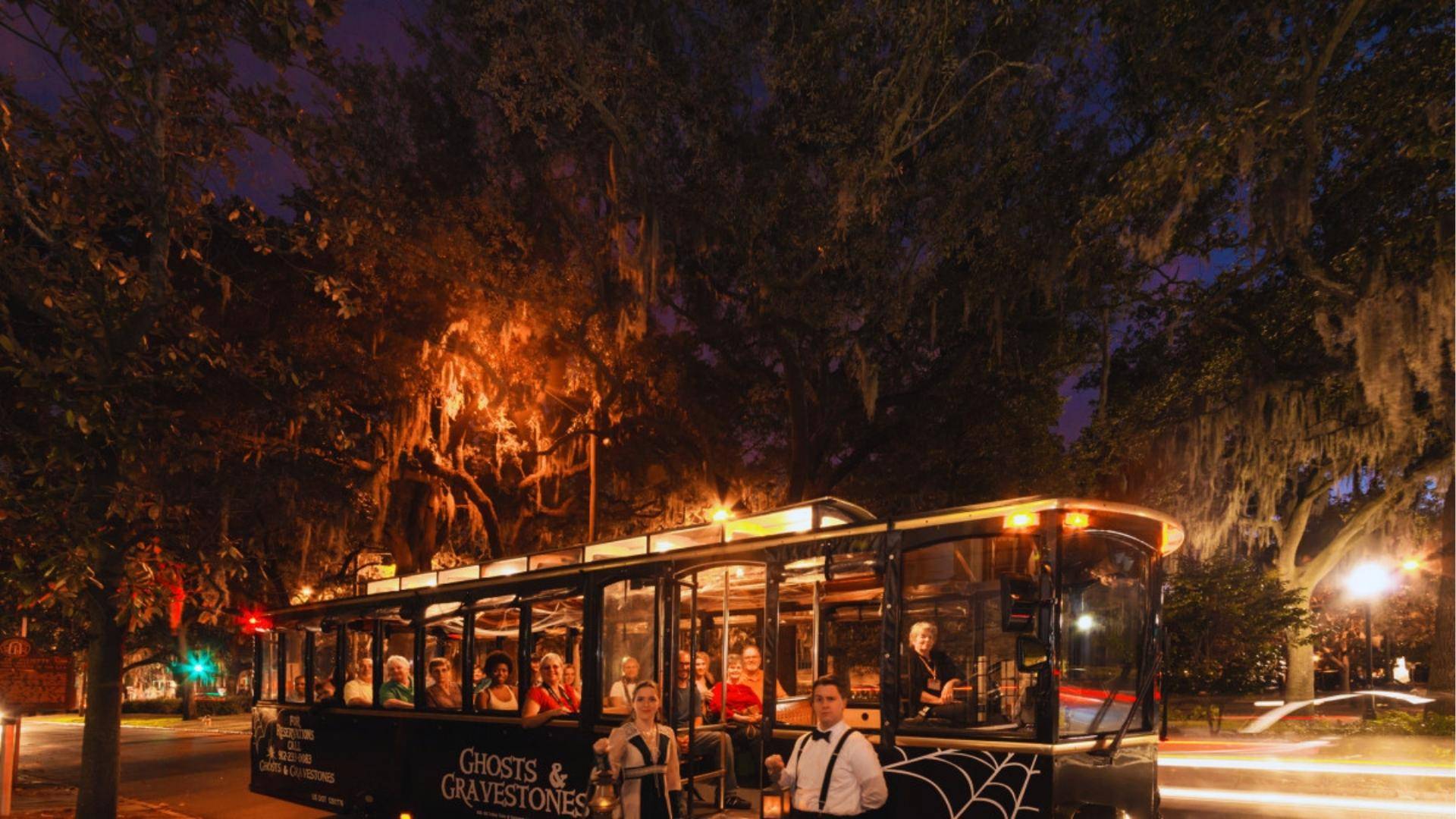 Ghosts and Gravestones haunted trolley tour at night under moss-draped oaks in Savannah.