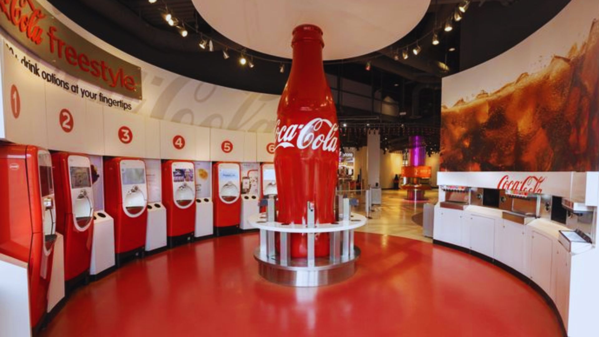 Giant Coca Cola bottle stands inside the World of Coca Cola tasting room with interactive soda stations.