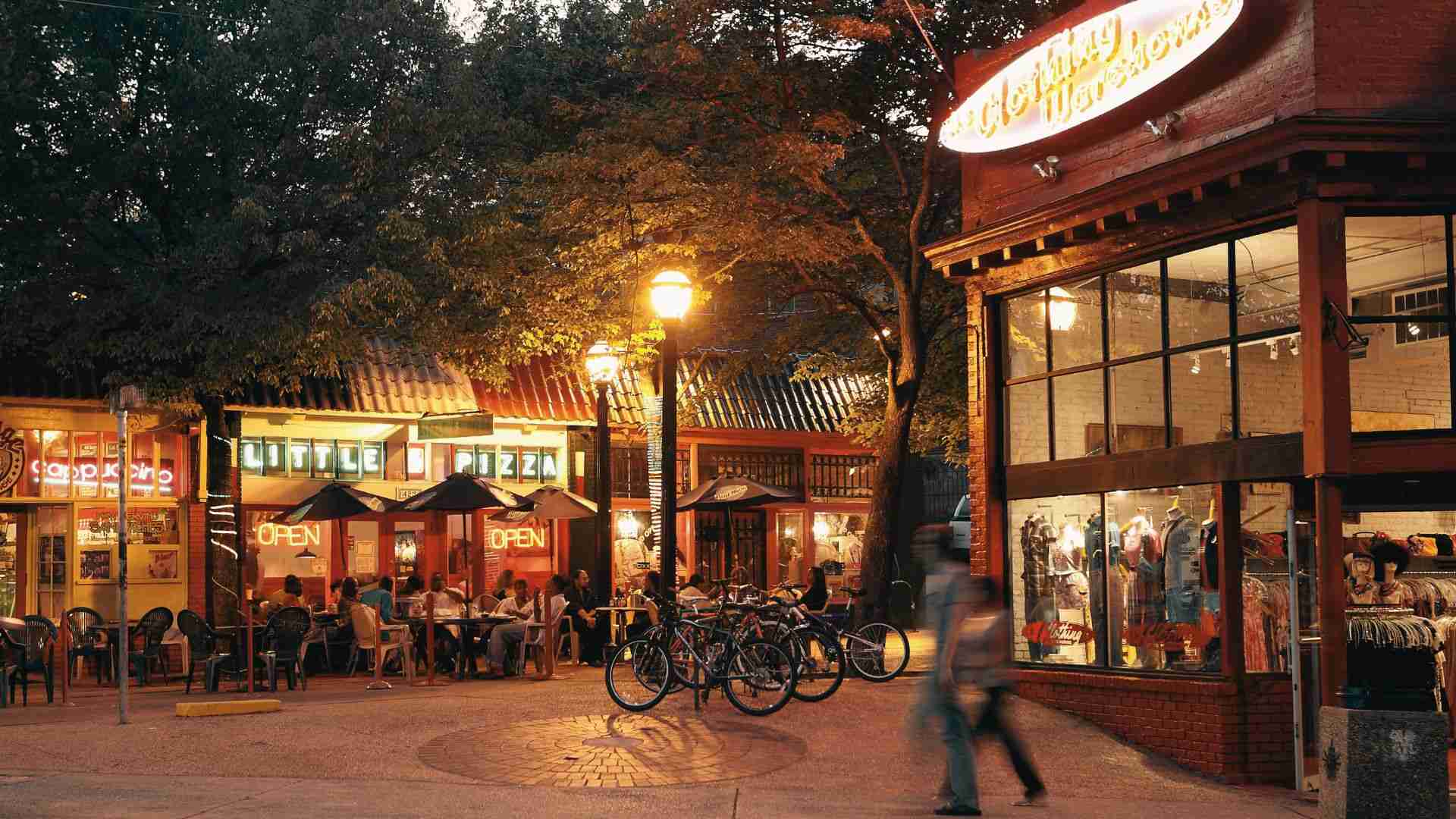 Evening scene at Little Five Points featuring outdoor dining, storefronts, and bicycles in Atlanta Georgia.