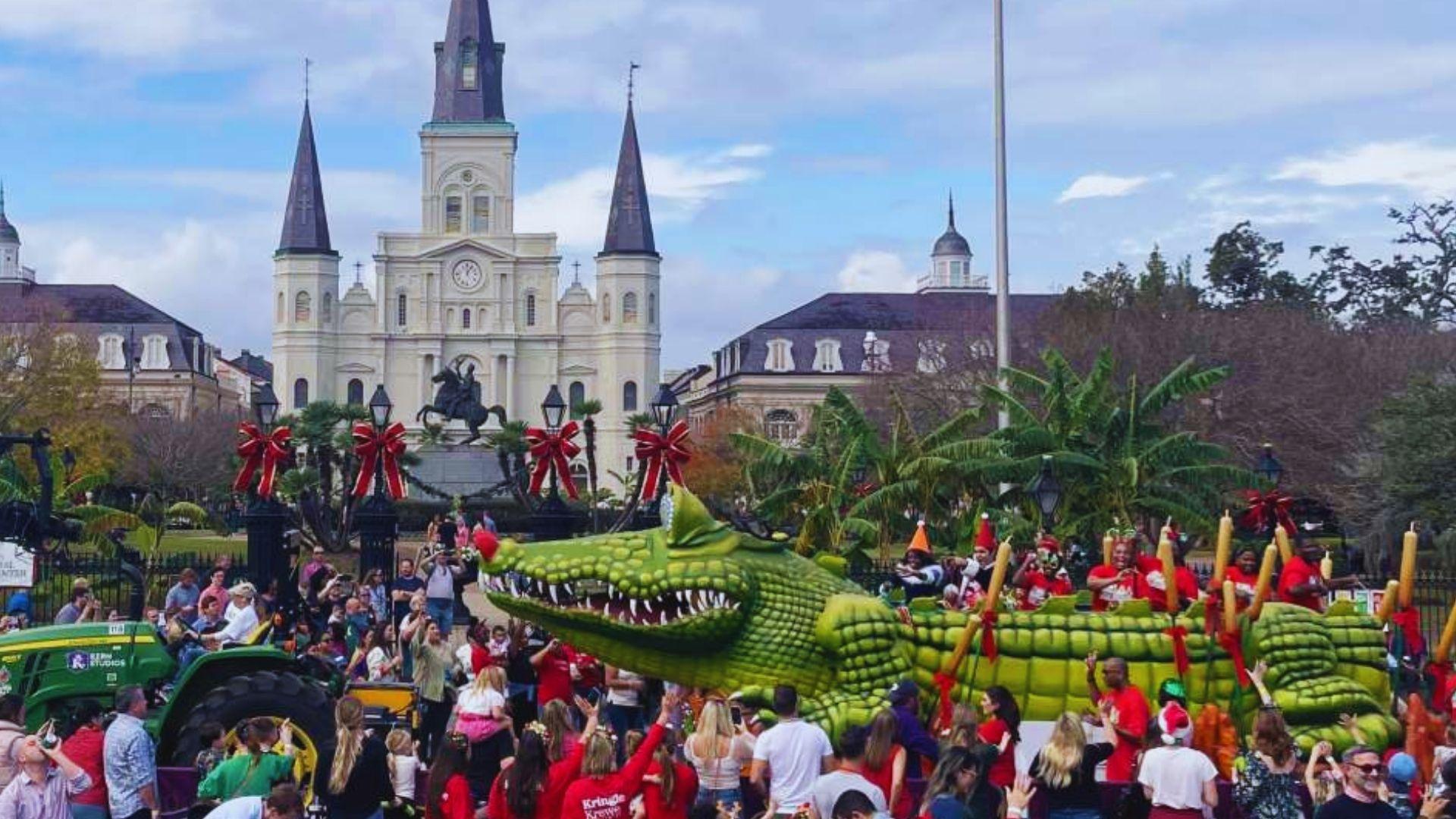 Daytime holiday parade float shaped like giant green alligator with Santa in sleigh, St. Louis Cathedral background
