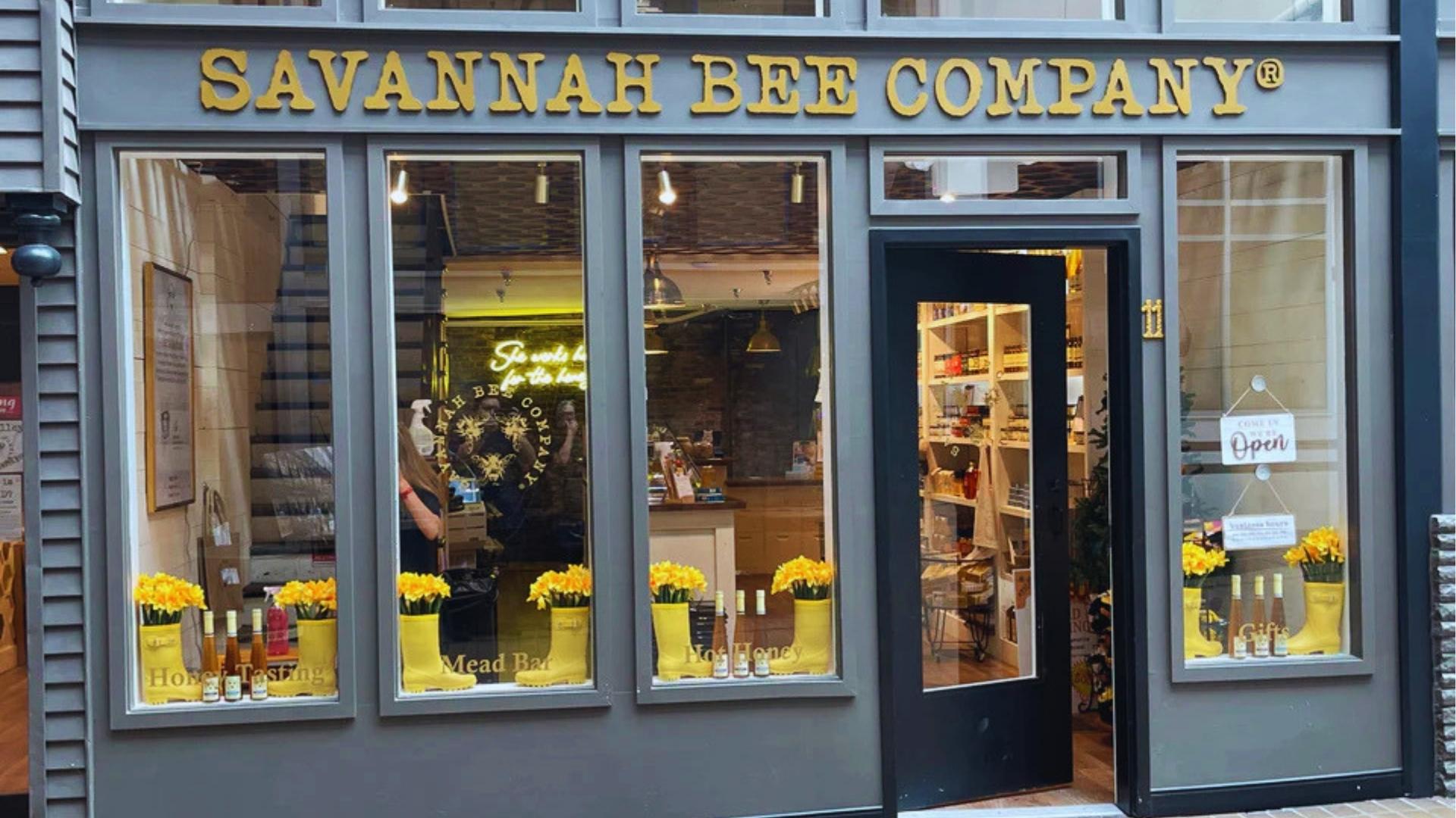 Savannah Bee Company storefront with yellow flower boots and honey tasting display on River Street.