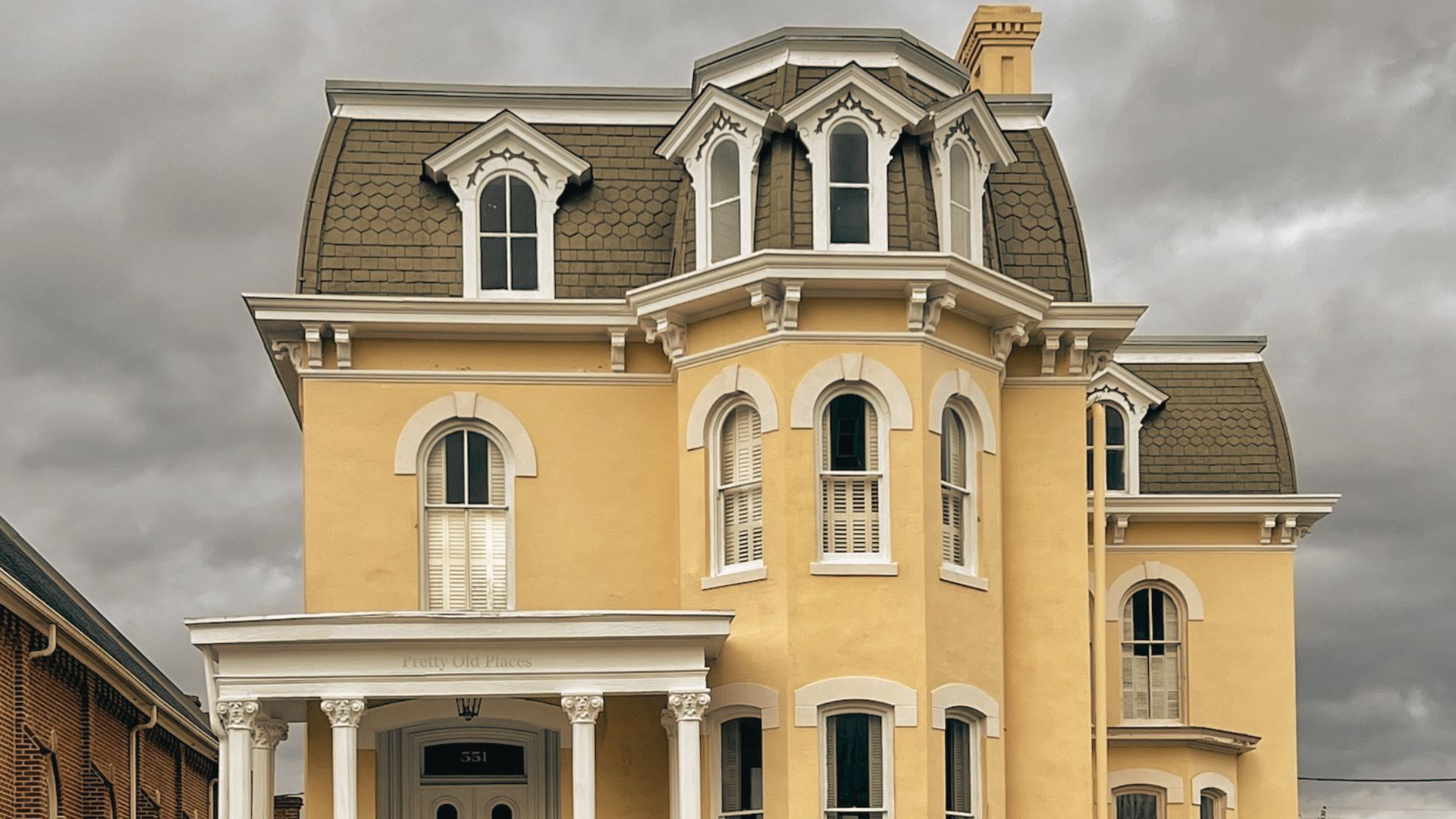  Historic yellow Augusta home with elegant dormer windows and covered porch beneath cloudy afternoon skies.