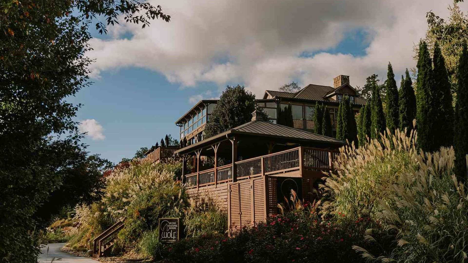 A scenic house on a hill surrounded by lush trees and bushes in Dahlonega, GA, showcasing the area's well known vineyard.