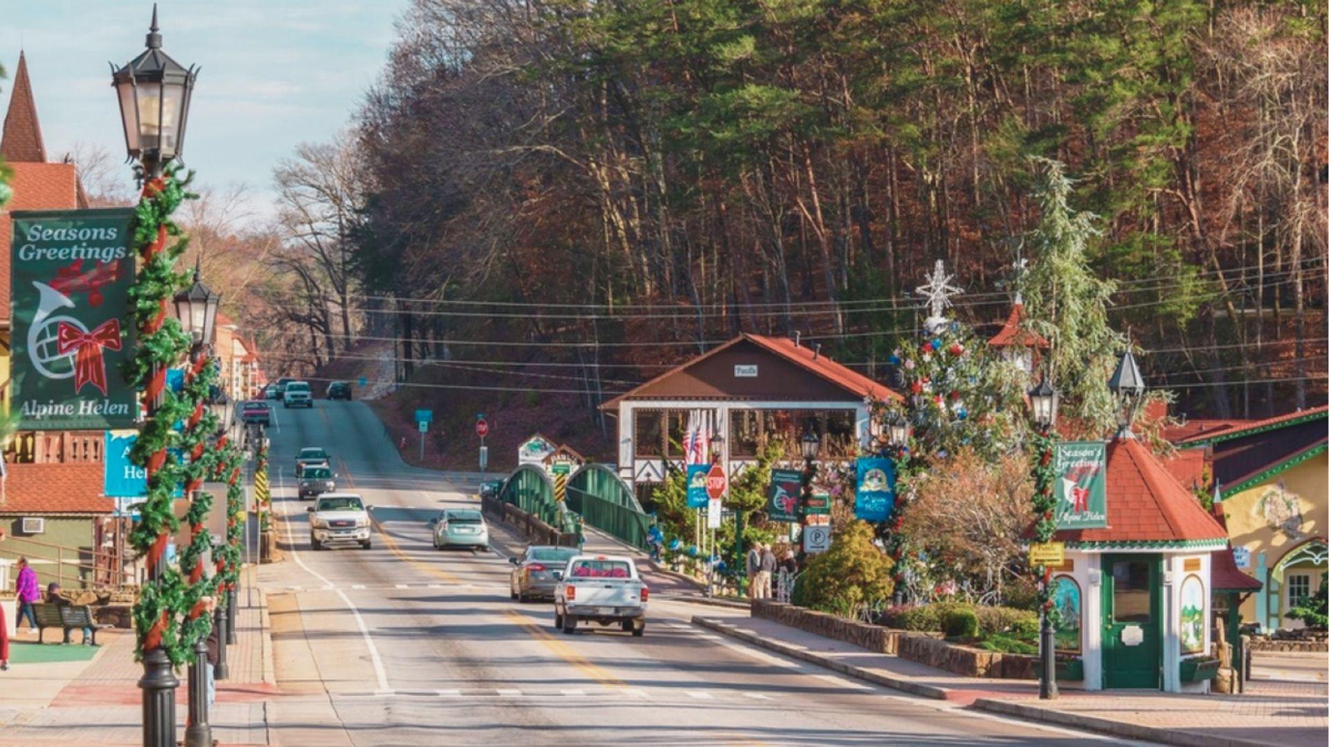 Helen, Georgia’s Main Street on a clear day with “Seasons Greetings” banners and garland wrapped lampposts.