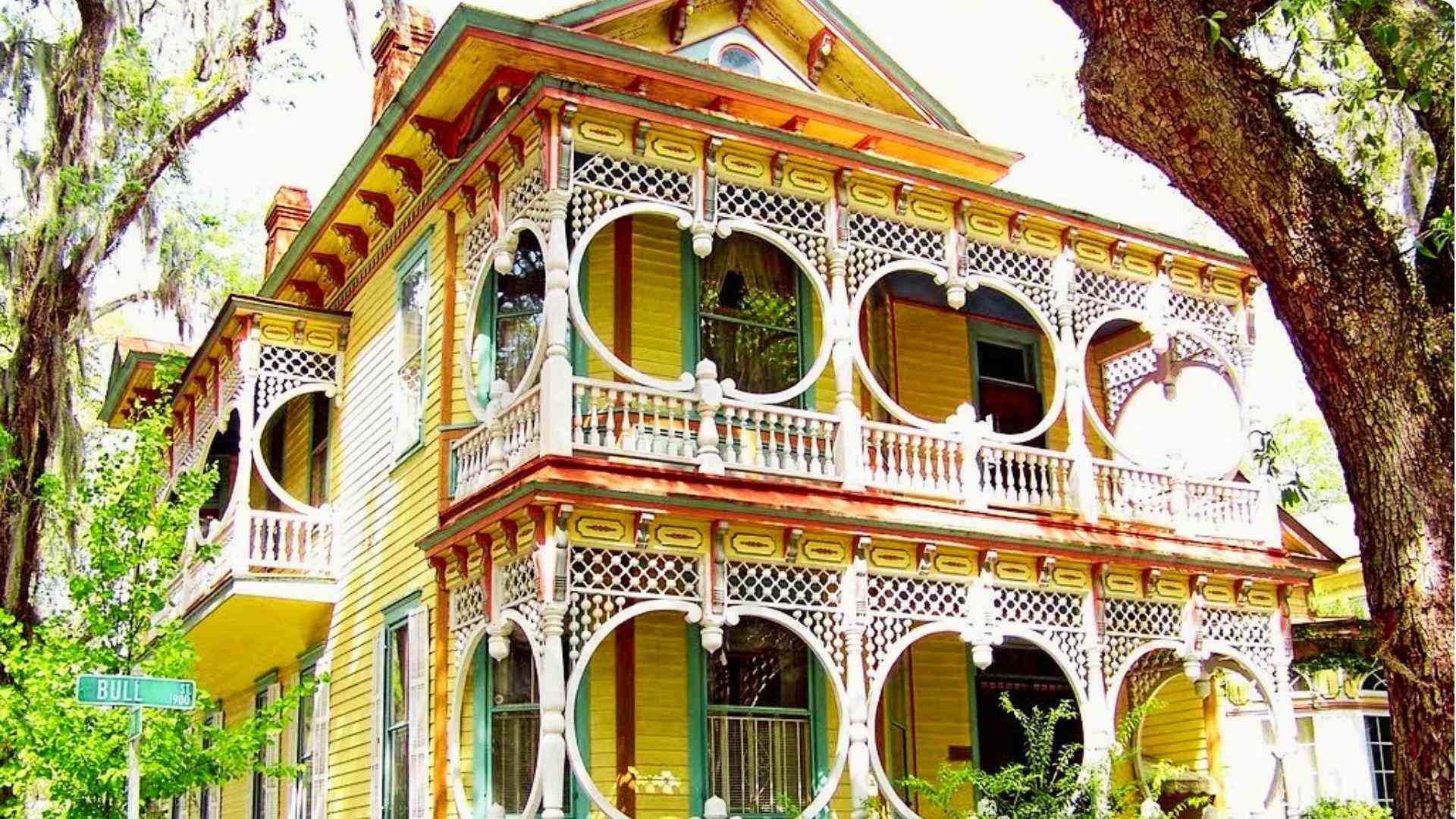 Vintage yellow house with rounded intricate windows and detailed designs.