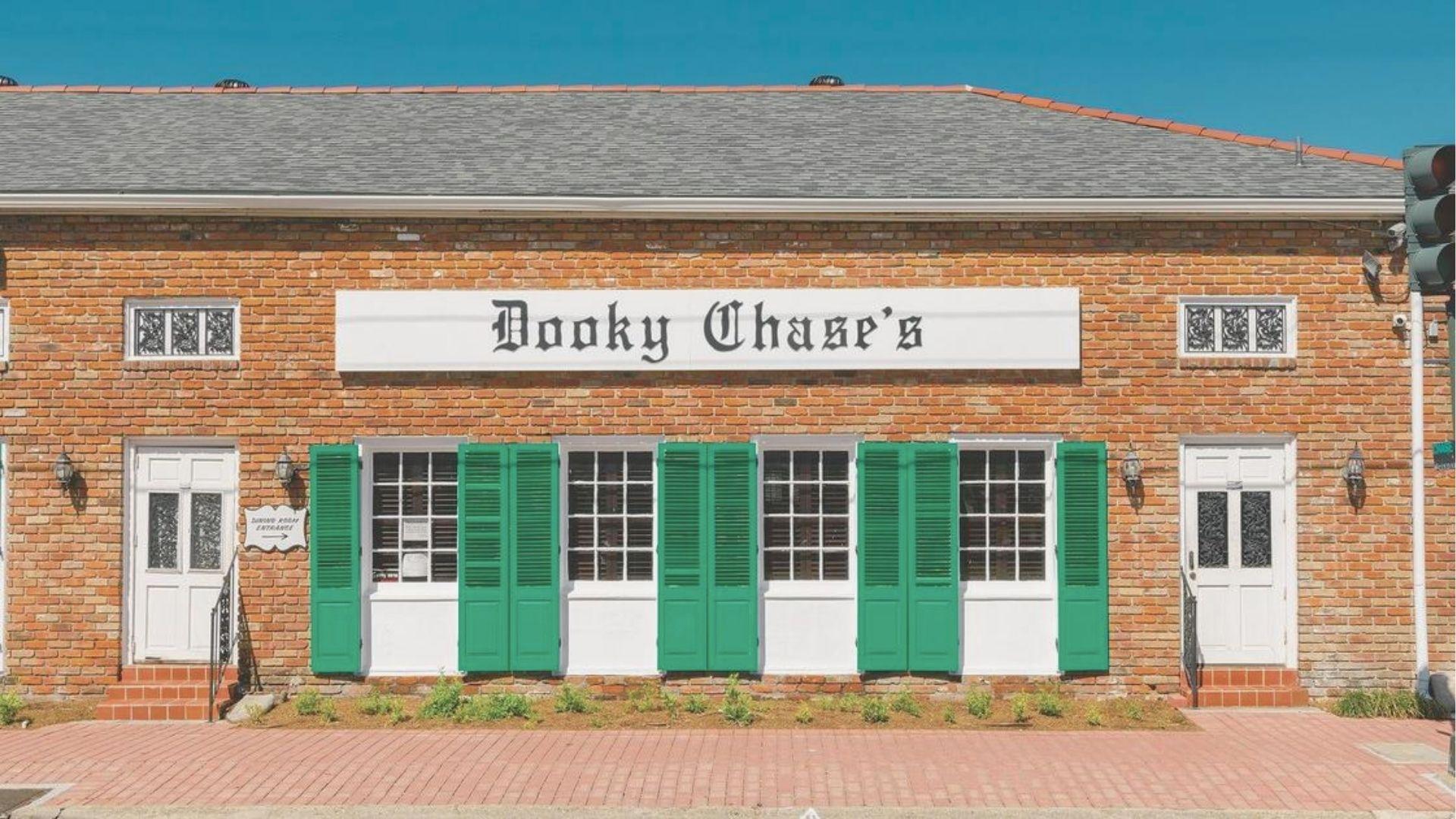 Brick facade of Dooky Chase's restaurant featuring green shutters and a bold white sign with black lettering.