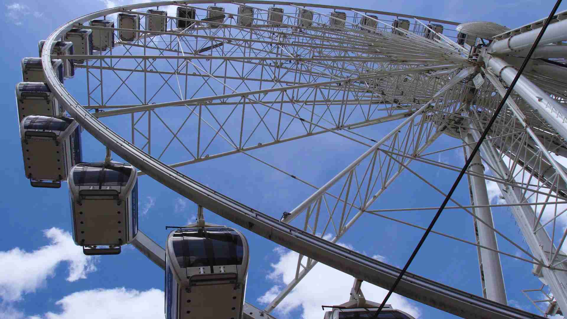SkyView Atlanta Ferris wheel cabins rise against a bright blue sky above Centennial Park district