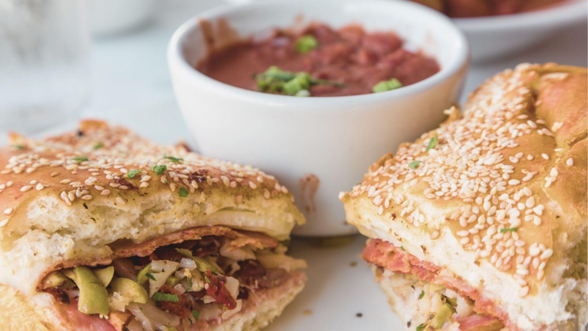 Taste an authentic muffuletta sandwich on sesame bread, loaded with olive salad, meats, and cheese.