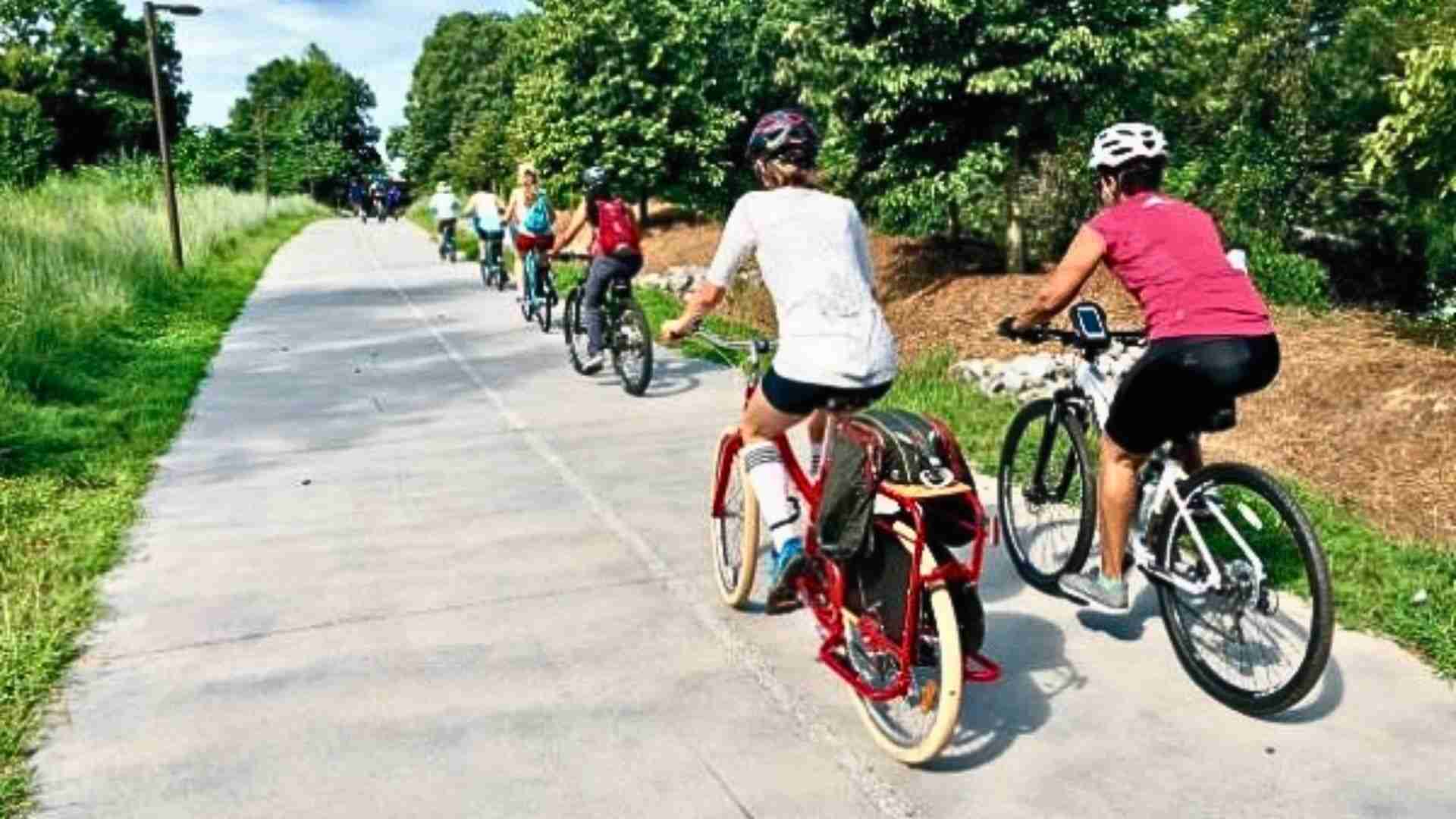 Participants enjoy a Beltline bike tour along a shaded paved trail lined with green trees.