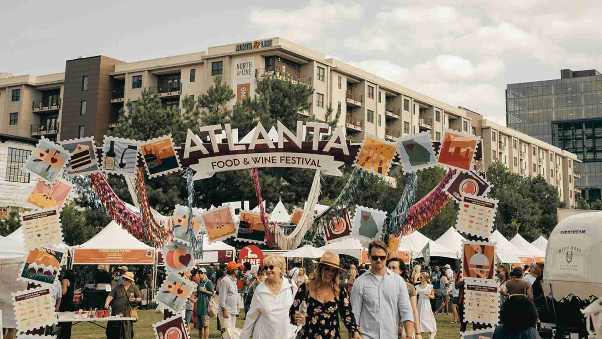 Crowds gather beneath the Atlanta Food and Wine Festival sign during an outdoor celebration event.