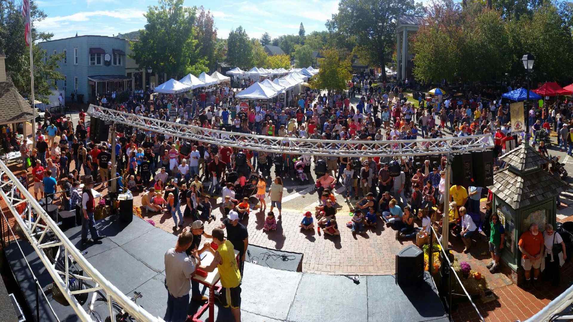 A large crowd gathers around a stage at the Rush Day Festival in Dahlonega, enjoying live performances and festivities.