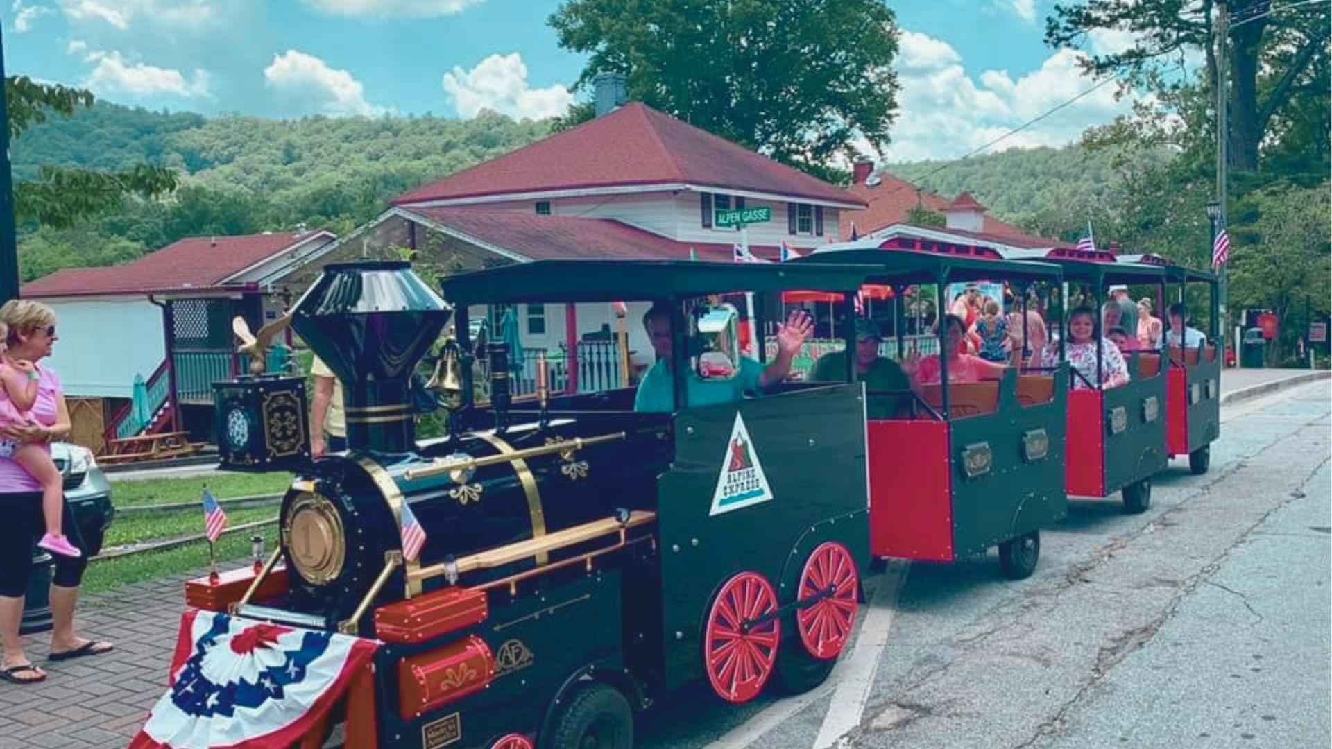 Alpine Express trackless train decorated with American flags and patriotic bunting rolls through Helen, GA.