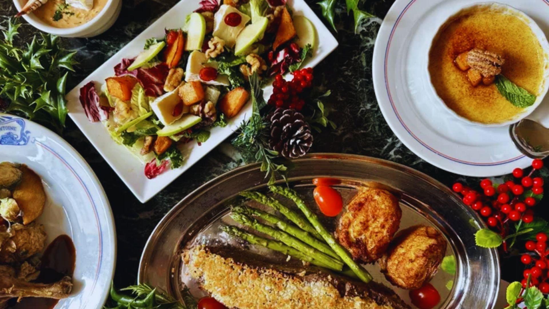 Holiday meal spread at Antoine’s Restaurant with creole dishes, pecan crusted fish, asparagus, salad, creme brulee, holly