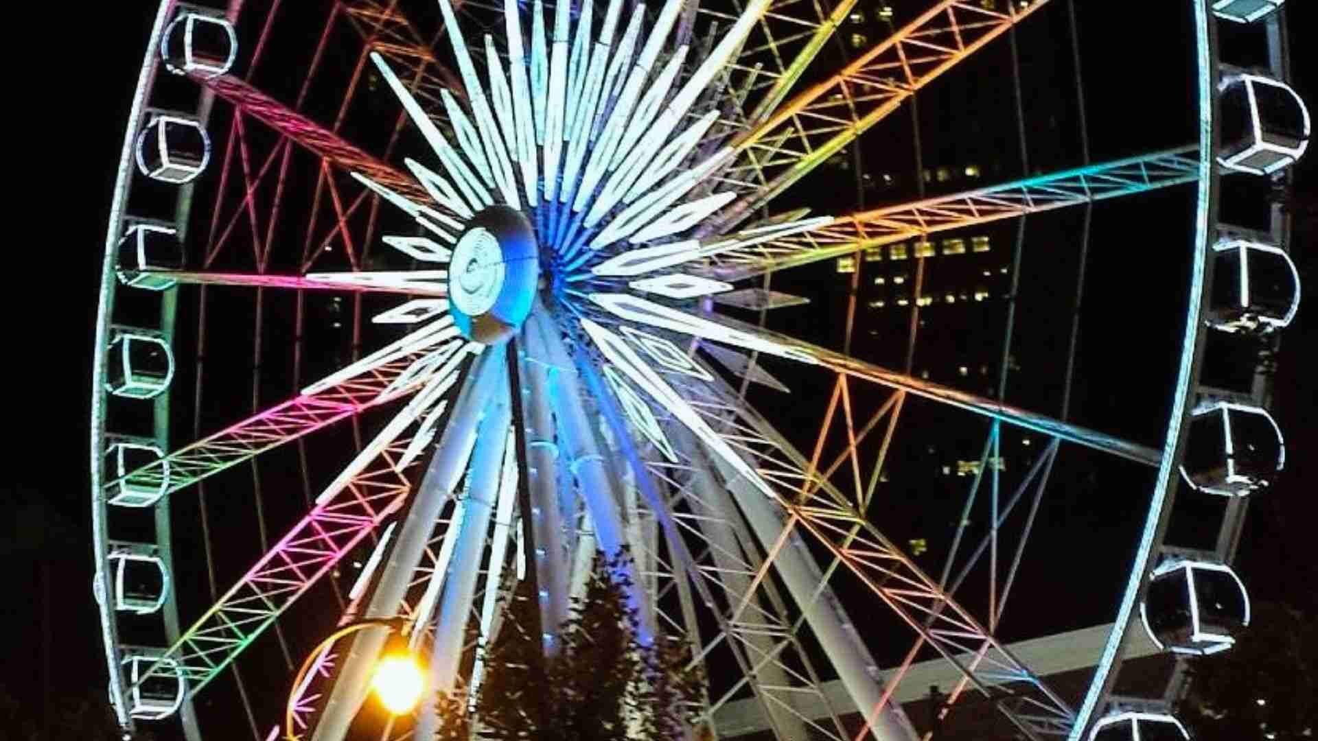 SkyView Atlanta Ferris wheel glows with colorful lights against the downtown Atlanta night skyline.