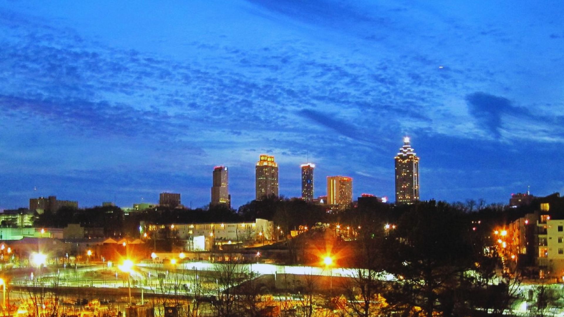 Atlanta Beltline illuminated at dusk with glowing skyscrapers beneath a deep blue evening sky