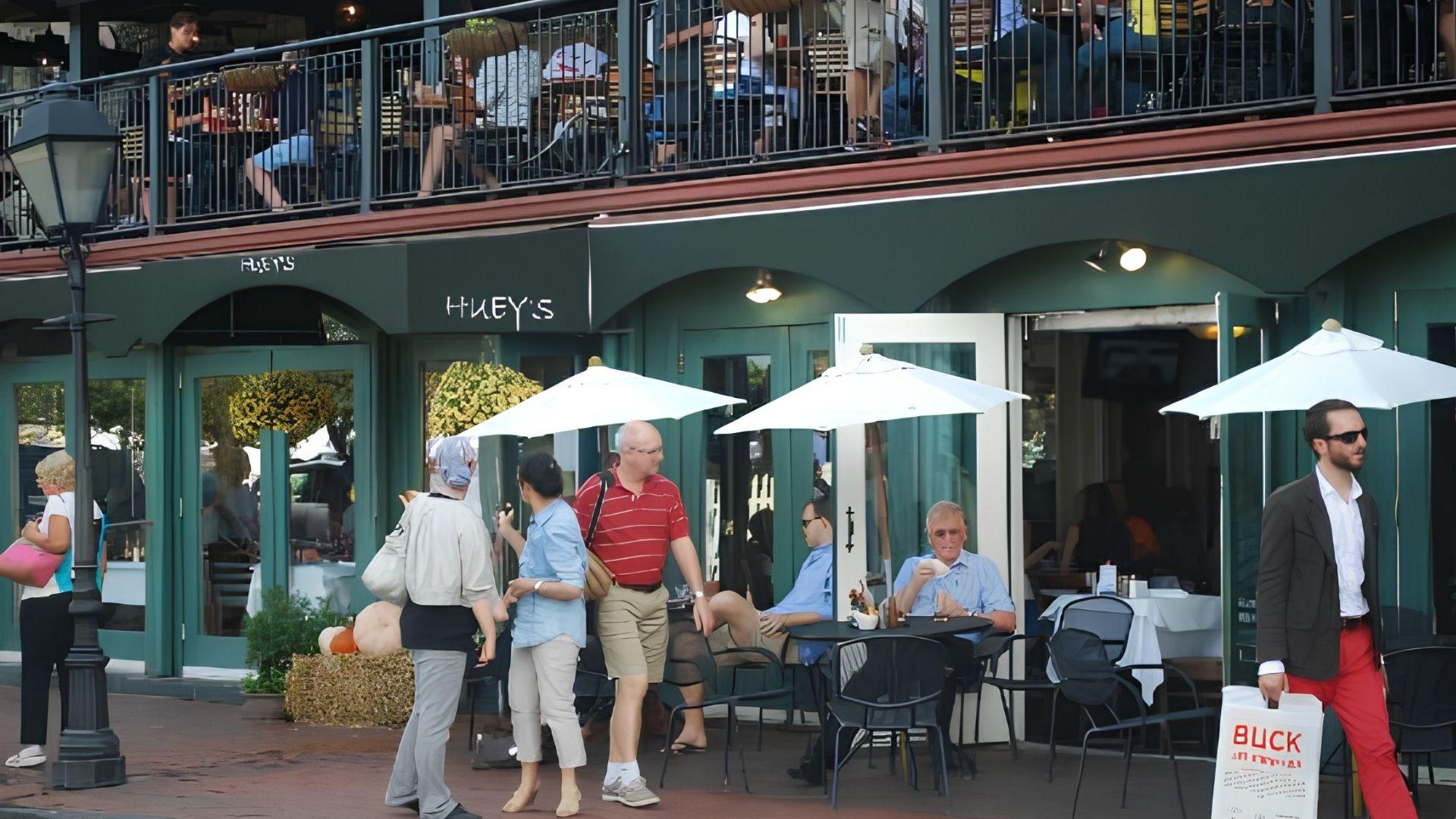 Huey’s green themed exterior with outside and rooftop seating and a huge crowd seated.
