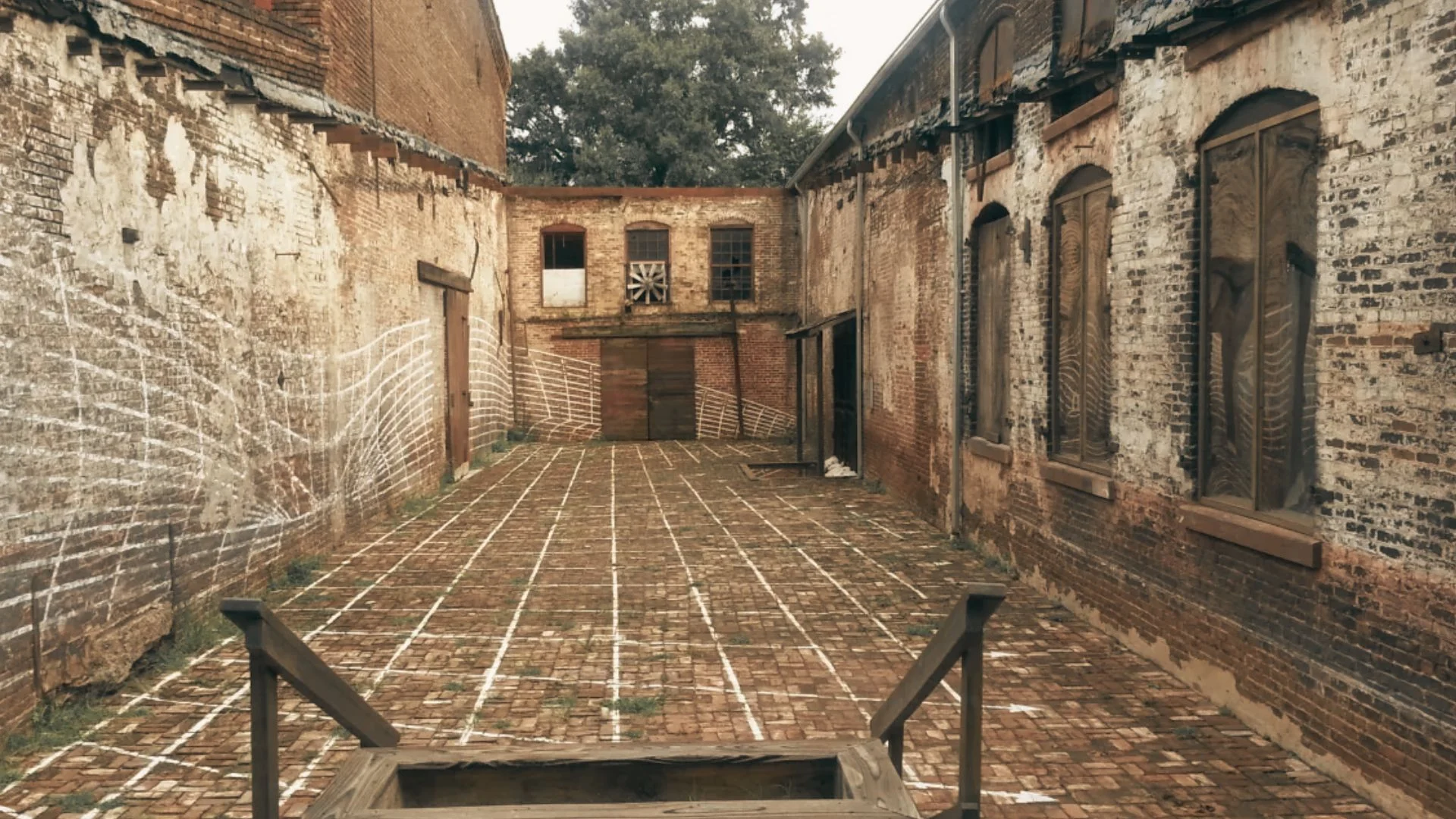 Brick courtyard at Goat Farm Arts Center with old industrial buildings and weathered walls surrounding open space.