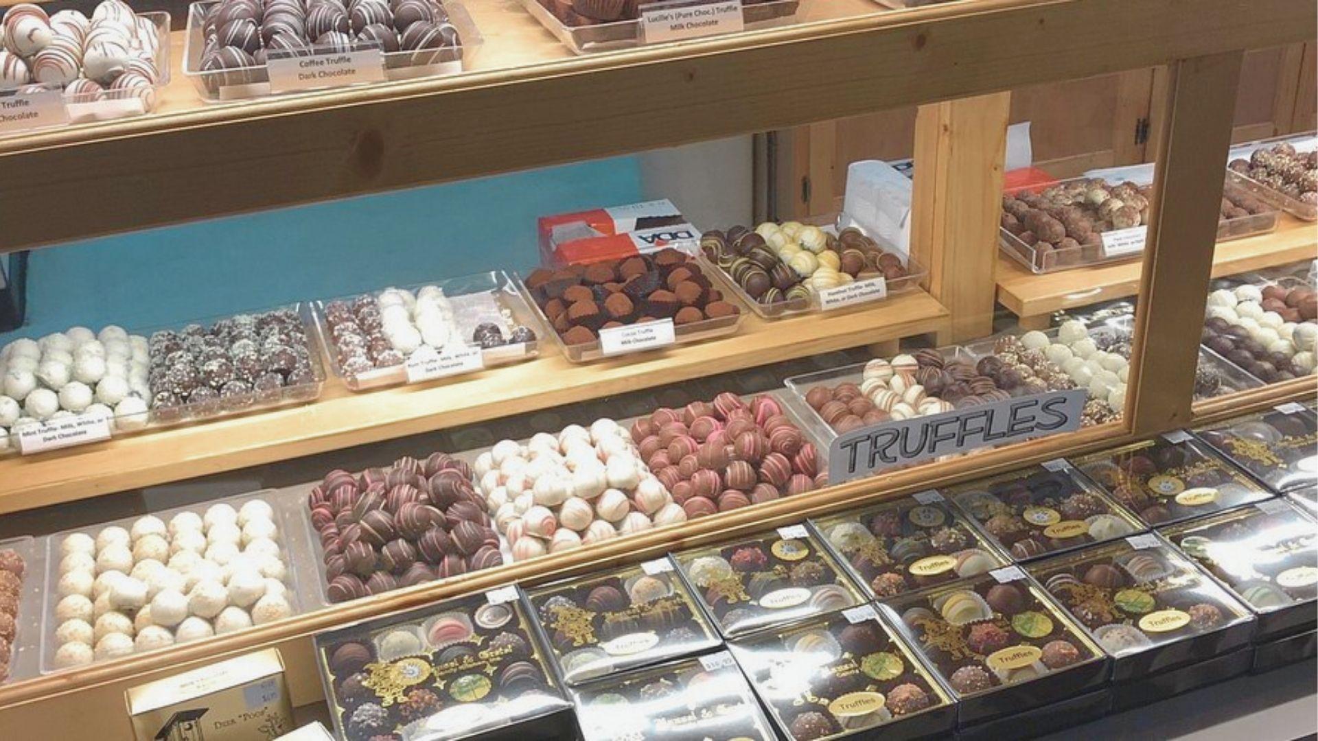 A bakery display case filled with assorted chocolate truffles, including coffee, mint, and milk chocolate flavors.