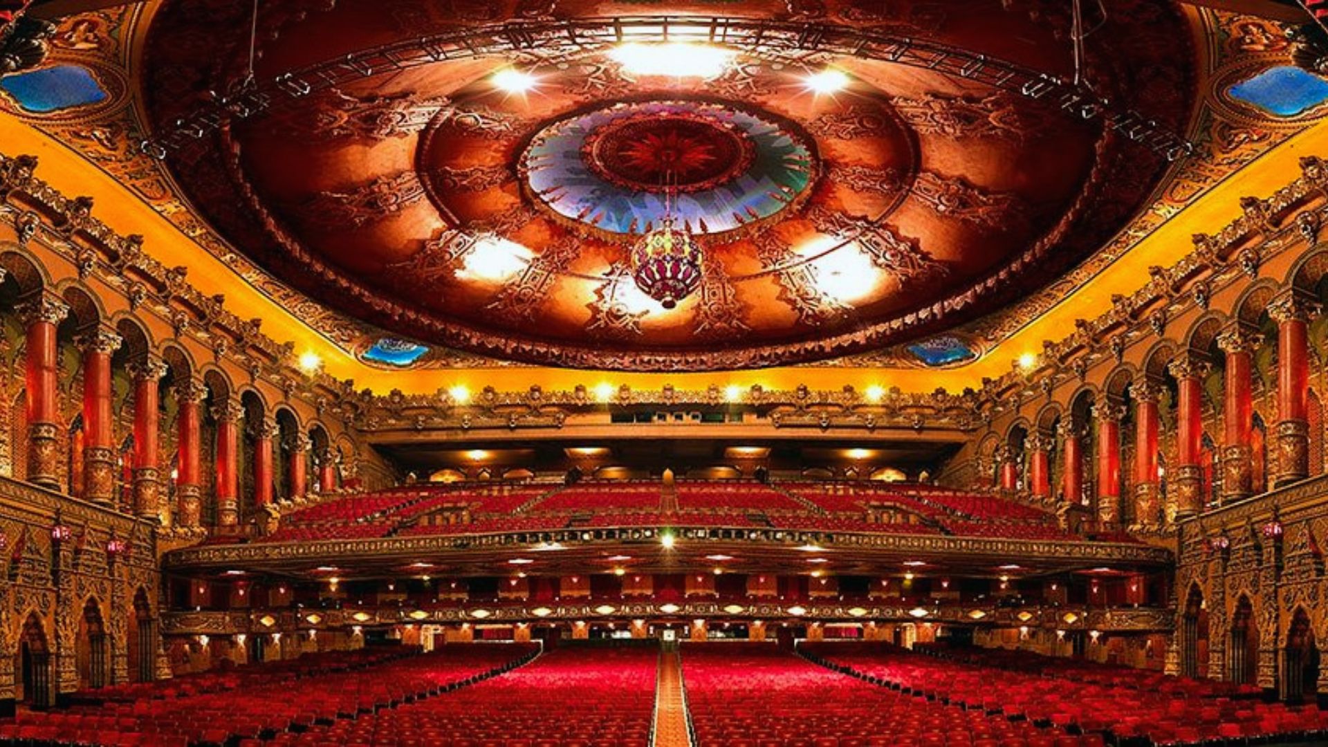 Fox Theatre interior featuring red seating, ornate balconies, and a richly decorated domed ceiling above.