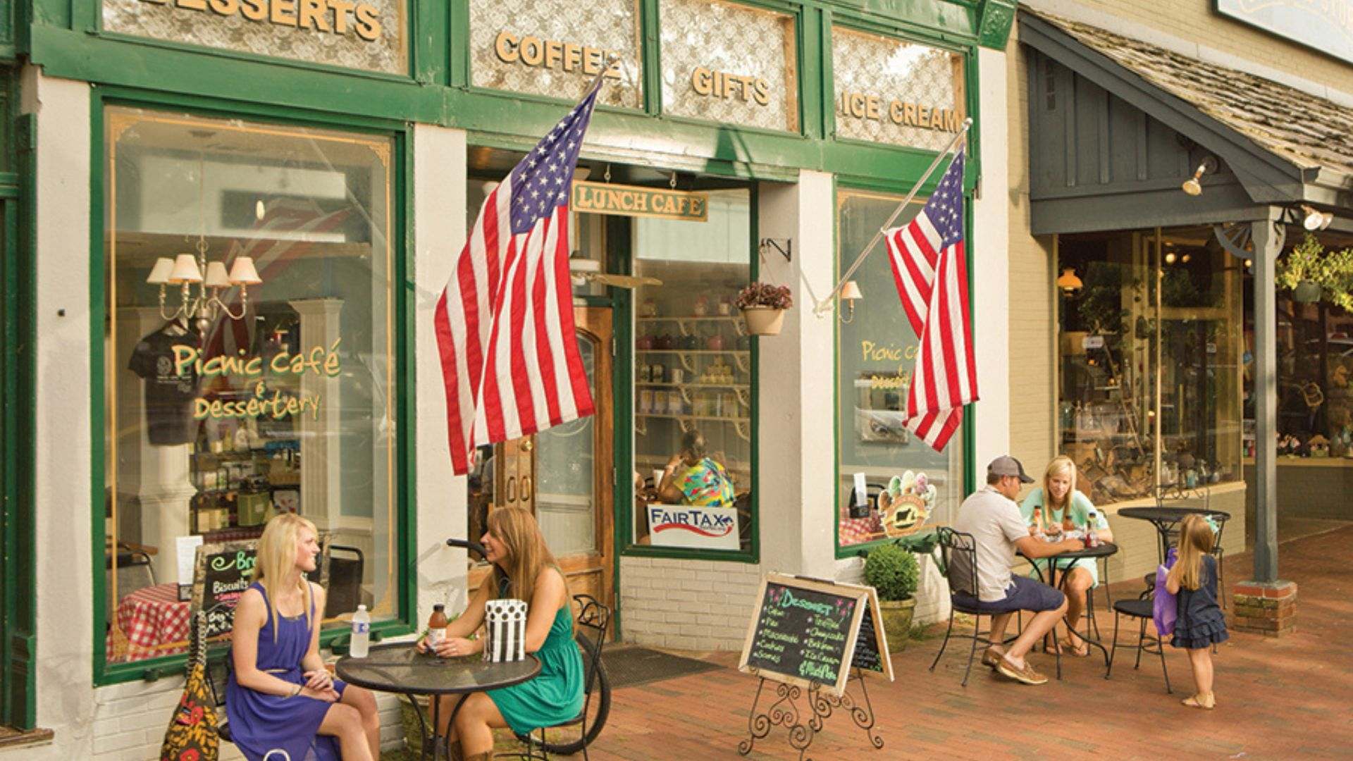 People gathered at outdoor tables in downtown Dahlonega, socializing and relaxing in a vibrant shopping area.