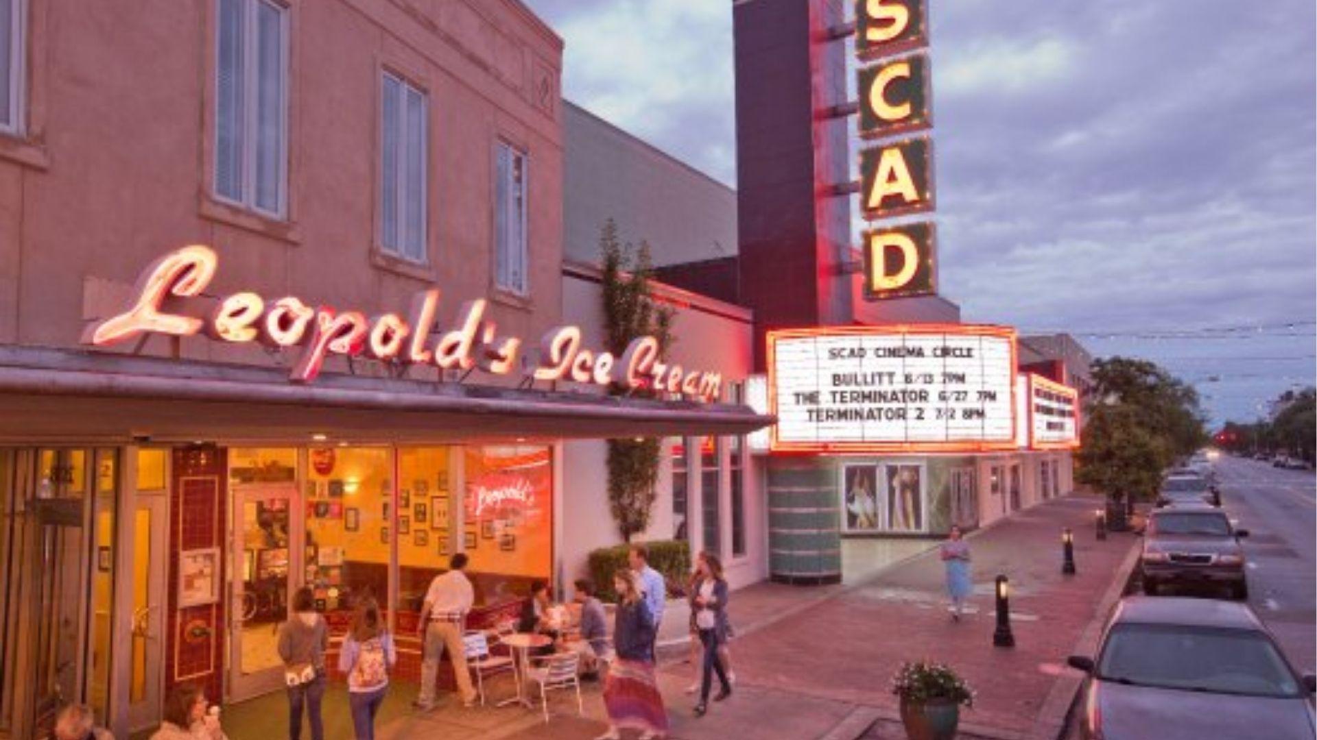 Leopold’s Ice Cream in red neon sign glowing in the evening, located in a busy street.