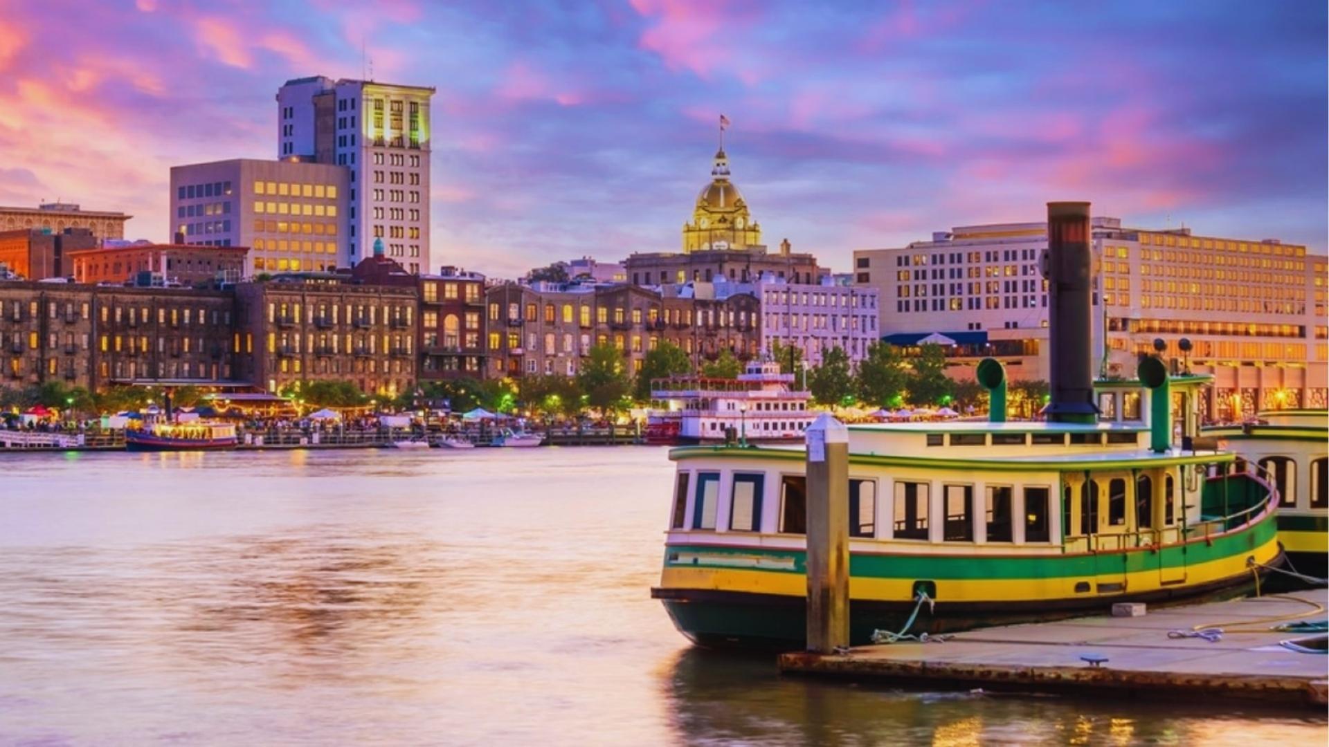 Savannah River Street at sunset with riverboat and gold-domed City Hall skyline.