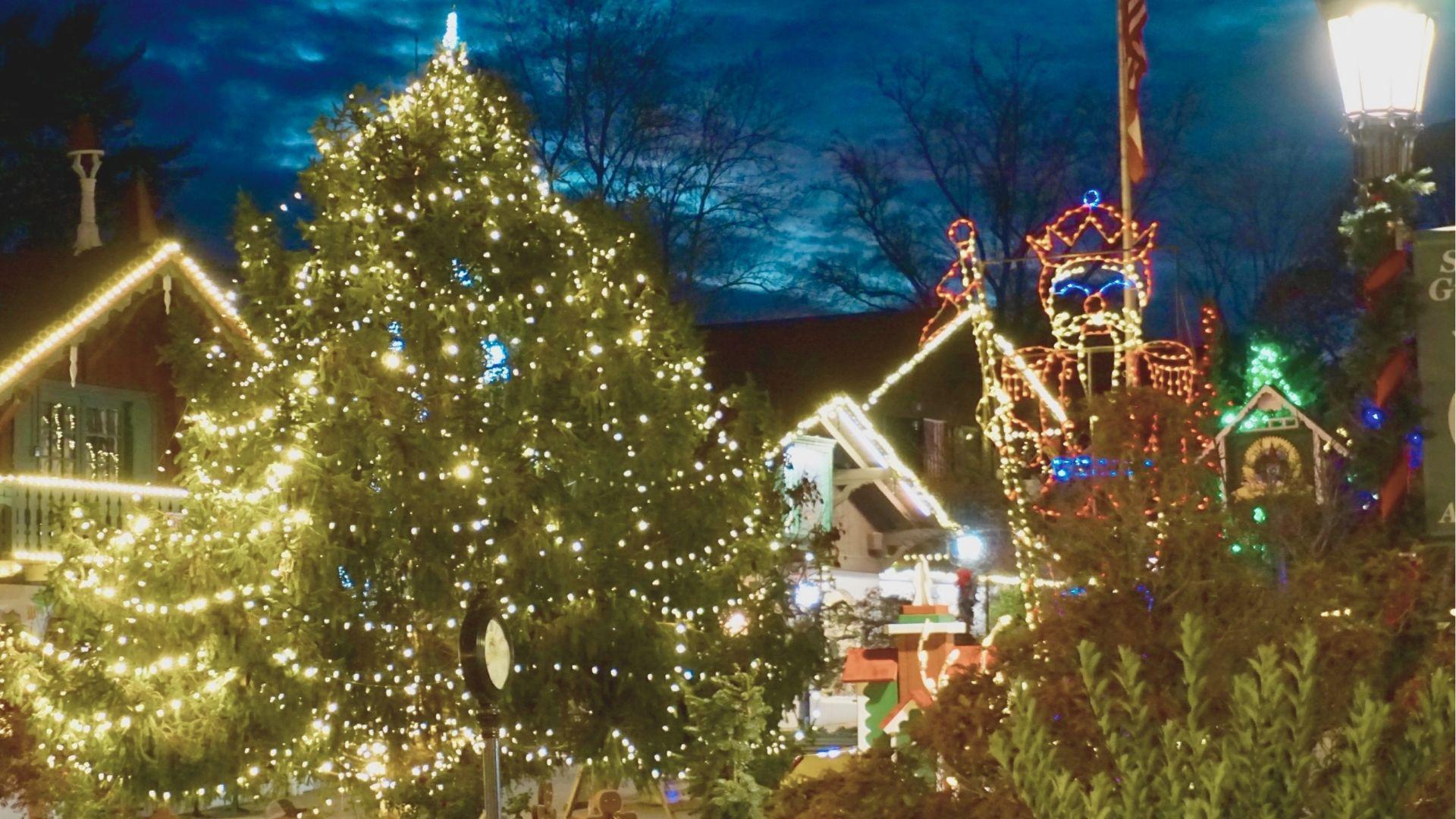 Downtown Helen at dusk with a giant Christmas tree and nutcracker light display glowing beside Bavarian buildings.