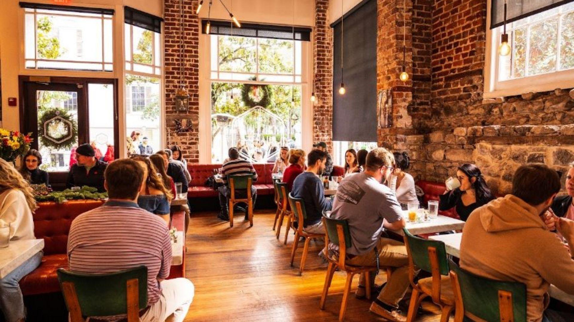 Interior seating of Collins Quarter with warm lighting, direct sunlight source and rustic themed walls.