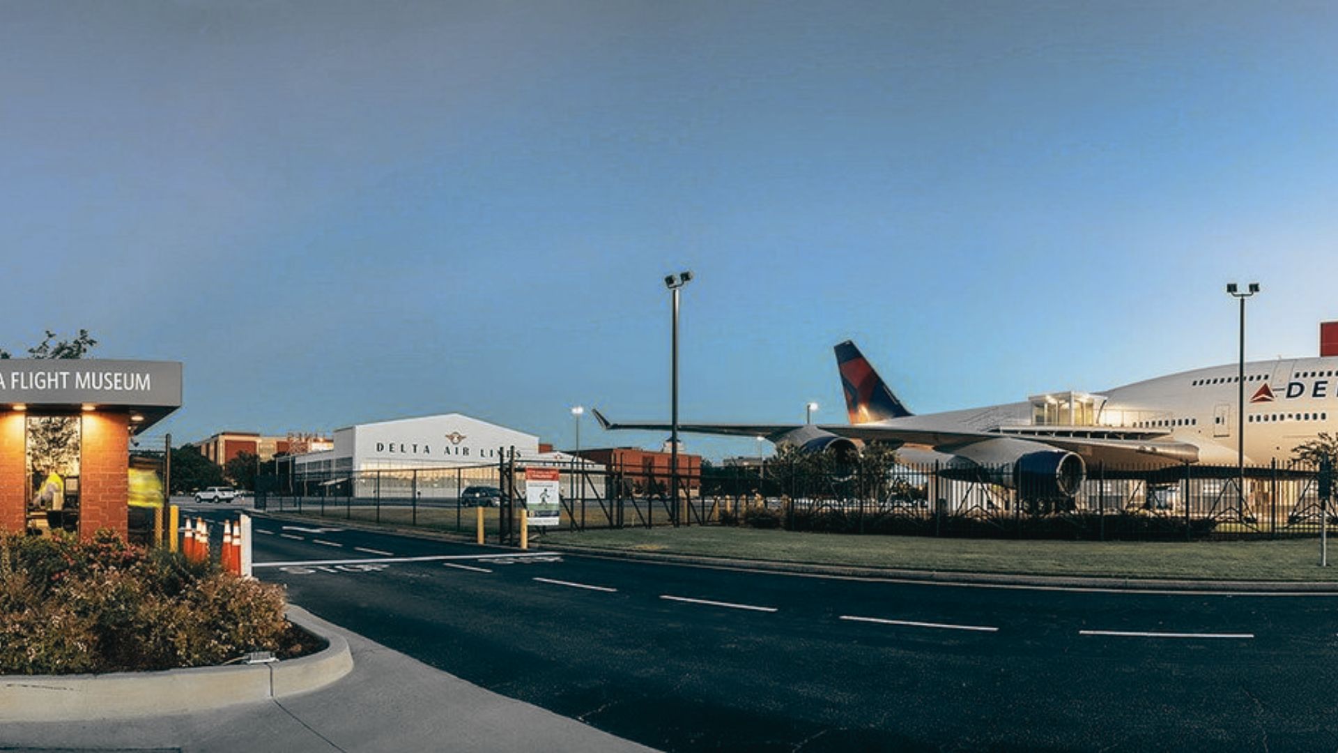 Delta Flight Museum entrance and historic aircraft display beside airport grounds during blue evening twilight sky.