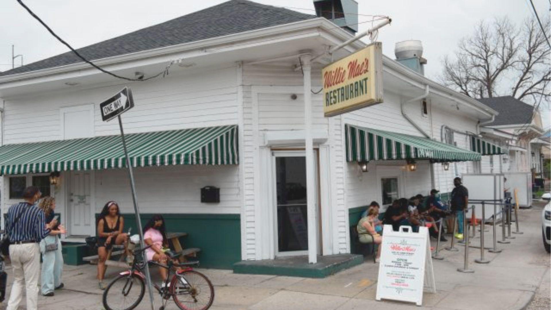 Exterior of Willie Mae's Restaurant, a white corner building with green-striped awnings and a vintage yellow sign.