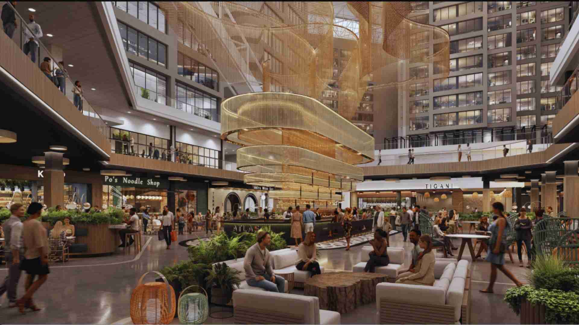 CNN Center atrium with suspended golden art installation, dining spaces, and people socializing indoors today.