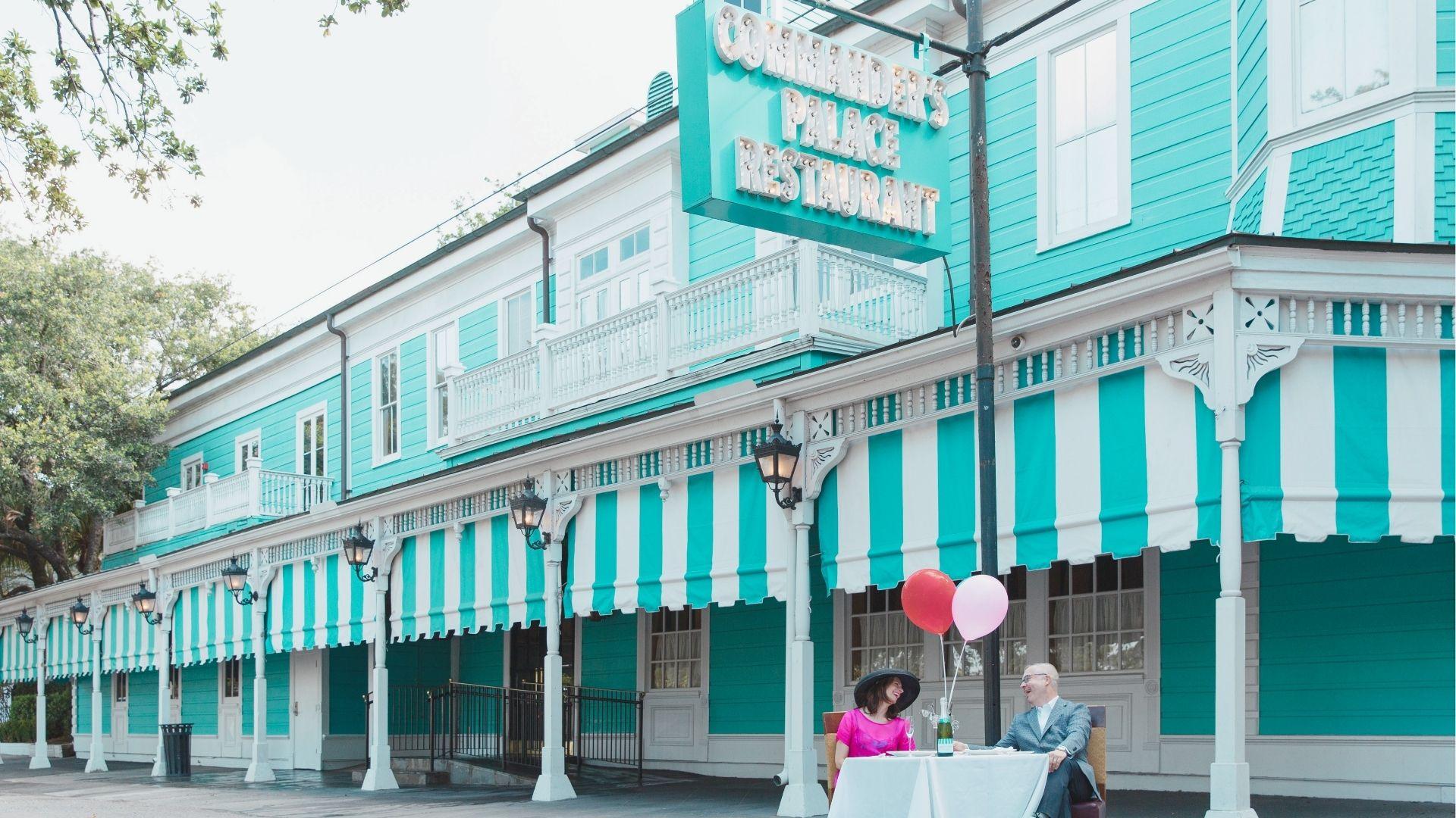 Commander's Palace exterior in turquoise with white striped awnings and a vintage marquee sign.