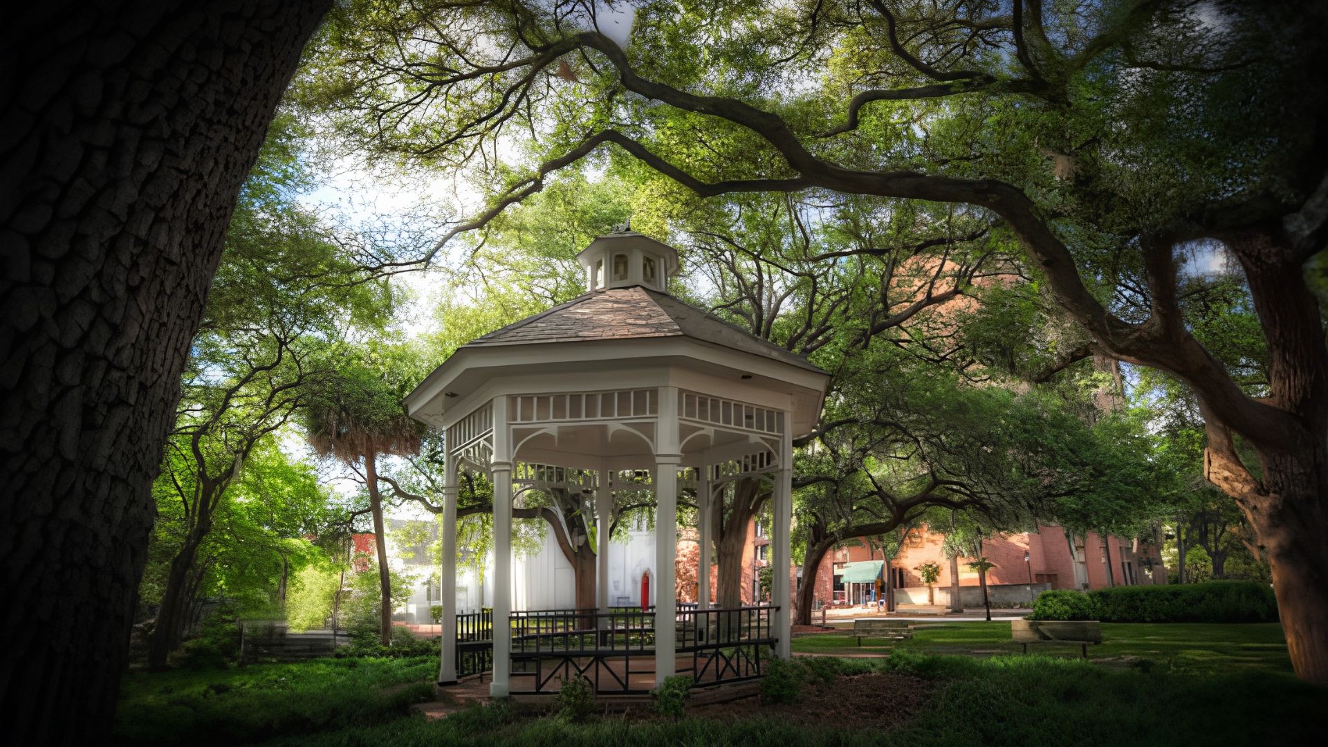 White Victorian-style gazebo framed by large oak trees in Whitefield Square, Savannah Georgia