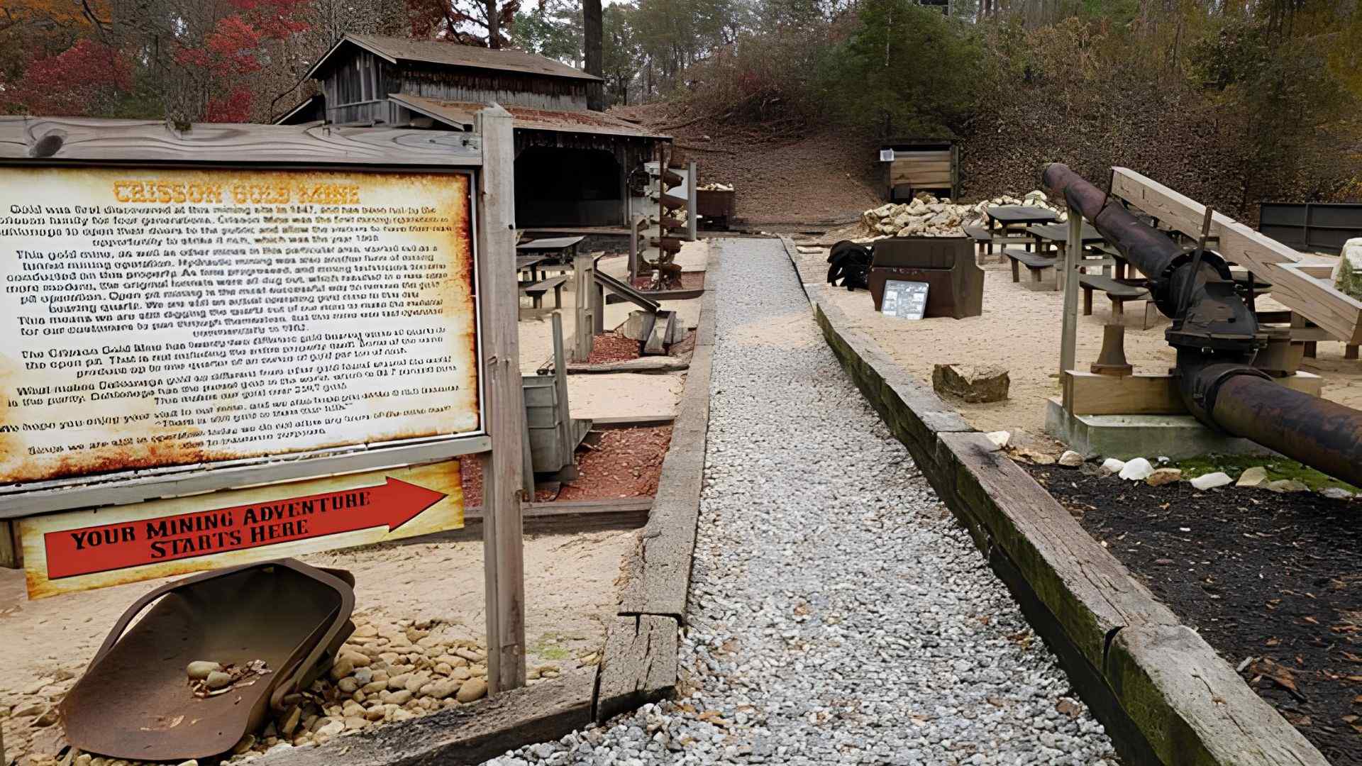 A rustic wooden board featuring the "Crisson Gold Mine" sign, surrounded by greenery and natural scenery.