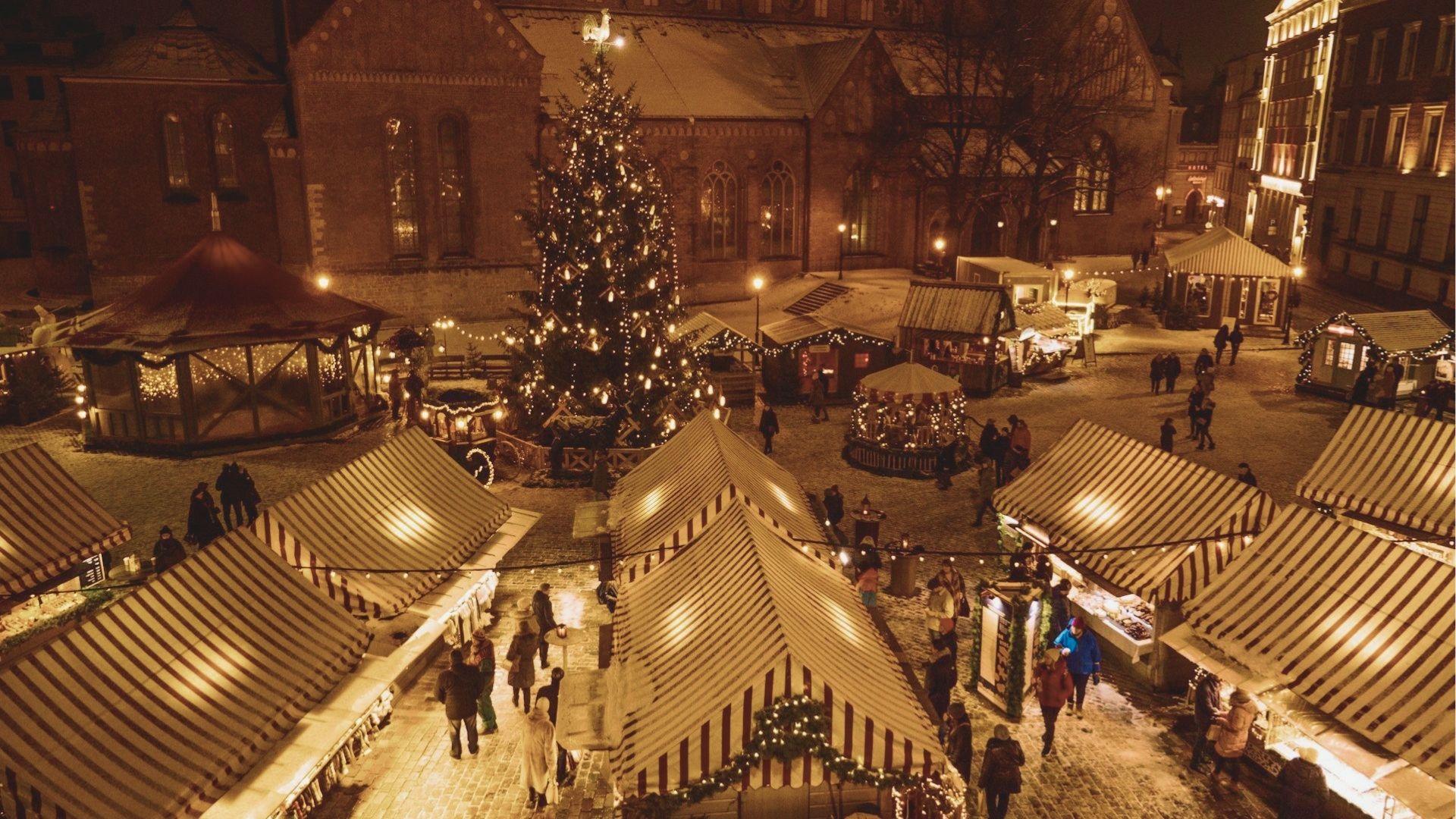 Overhead view of Helen’s Christkindlmarkt at night with striped vendor tents surrounding a lit Christmas tree.