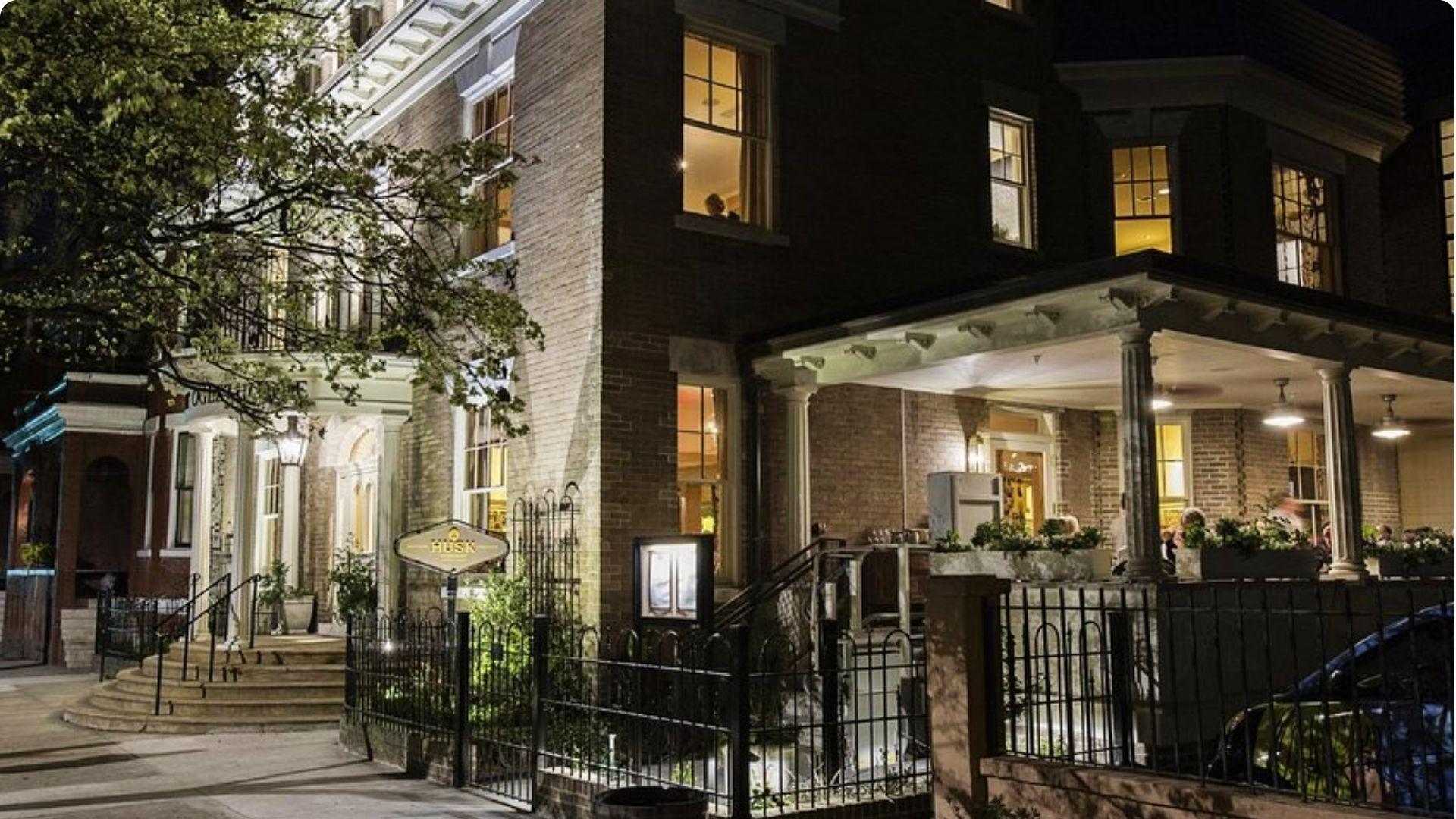 Nighttime exterior, an elegant multi-story brick Federal-style building with white columns.